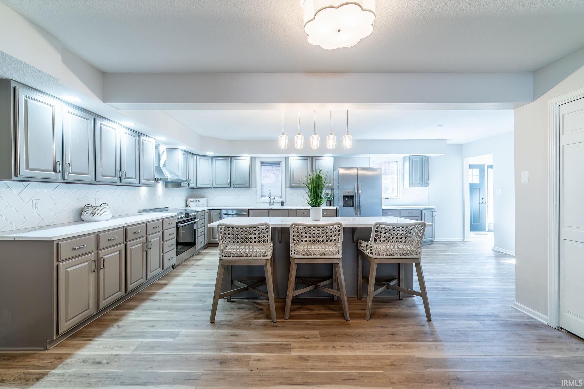 Kitchen featuring a breakfast bar area, tasteful backsplash, stainless steel appliances, a center island, and light wood finished floors