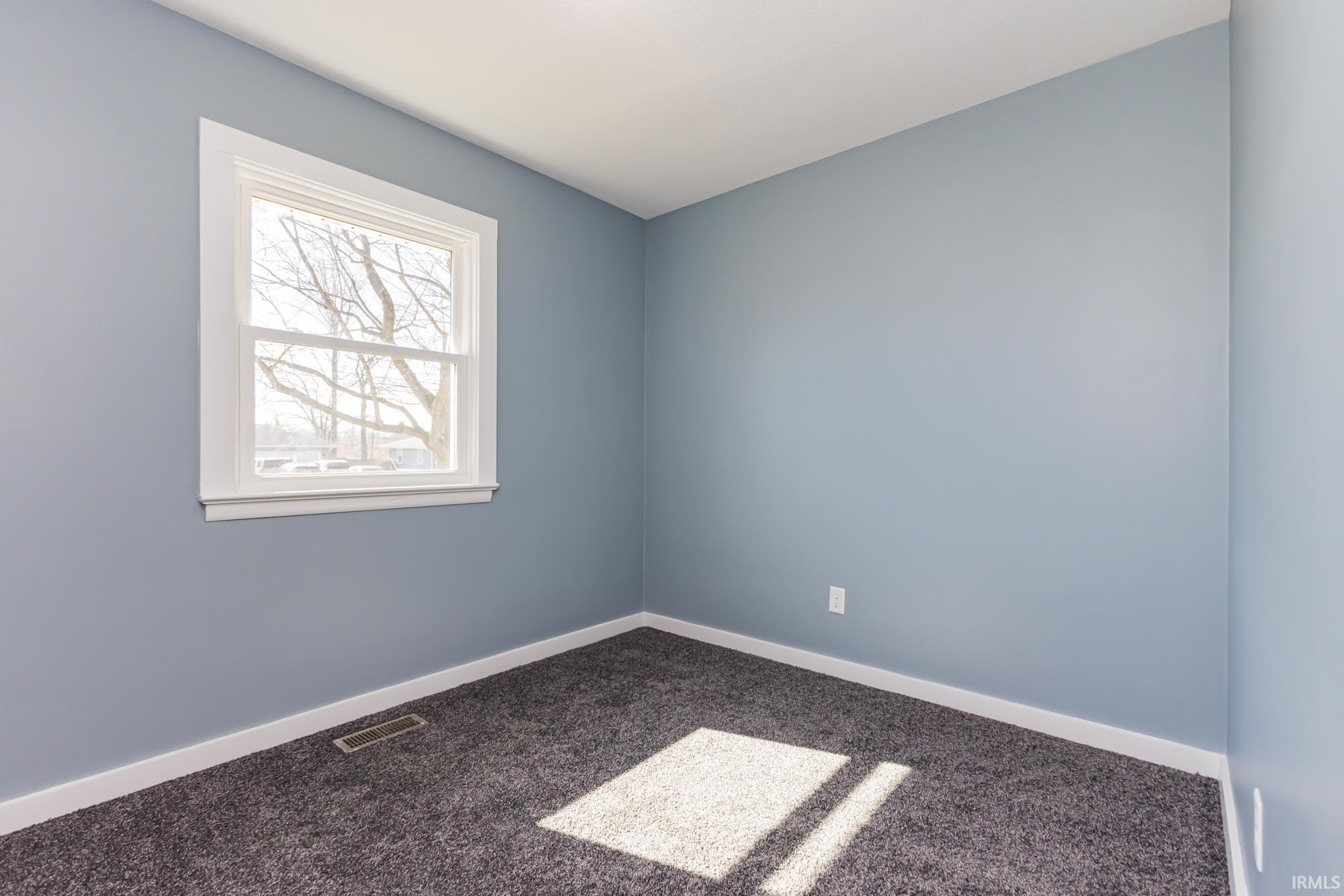 Spare room featuring baseboards and dark carpet