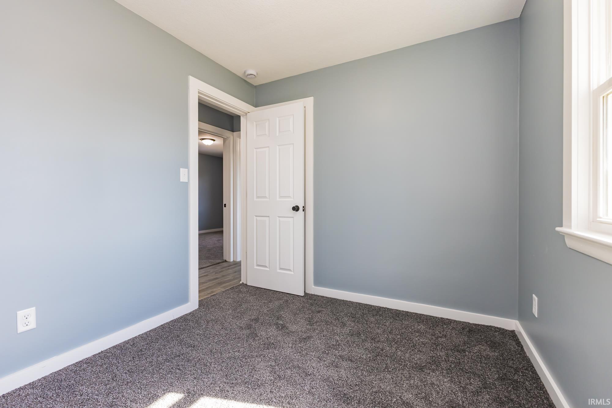 Empty room featuring baseboards and dark colored carpet