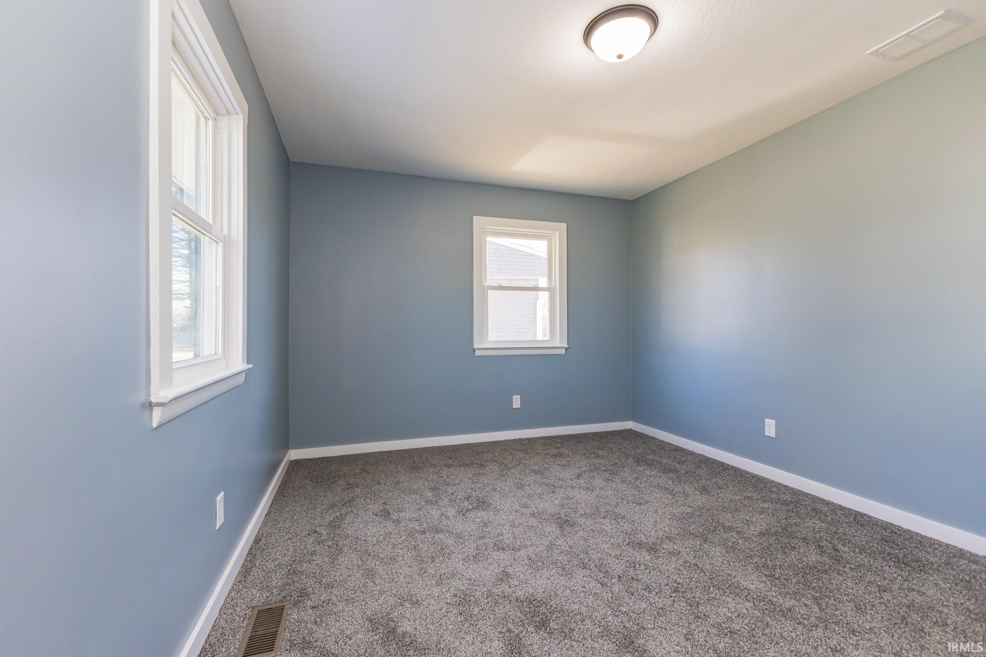 Carpeted spare room featuring baseboards