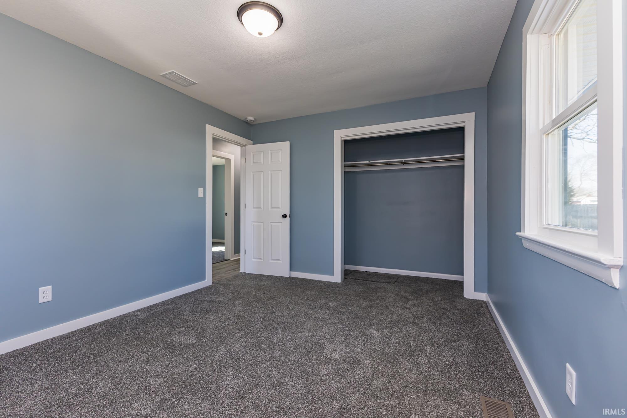 Unfurnished bedroom with dark colored carpet and a closet