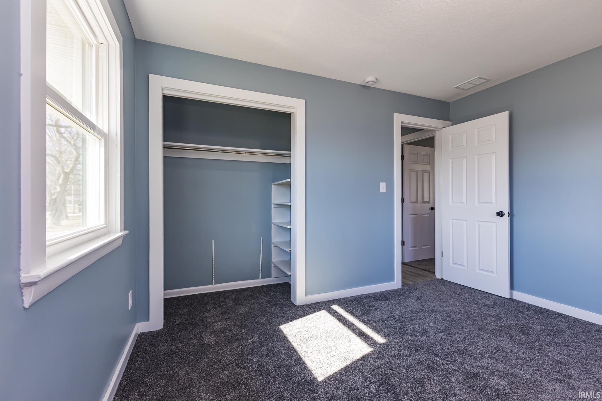 Unfurnished bedroom with dark carpet and a closet