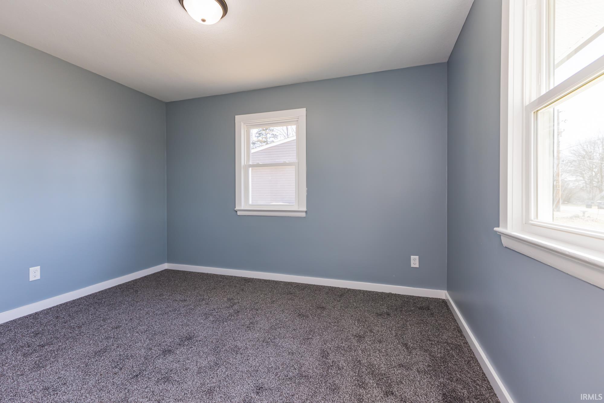 Carpeted spare room featuring baseboards