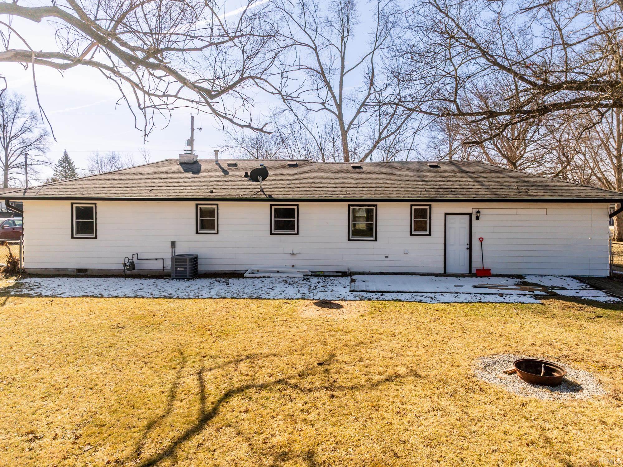 Rear view of house with a patio, a lawn, and a shingled roof
