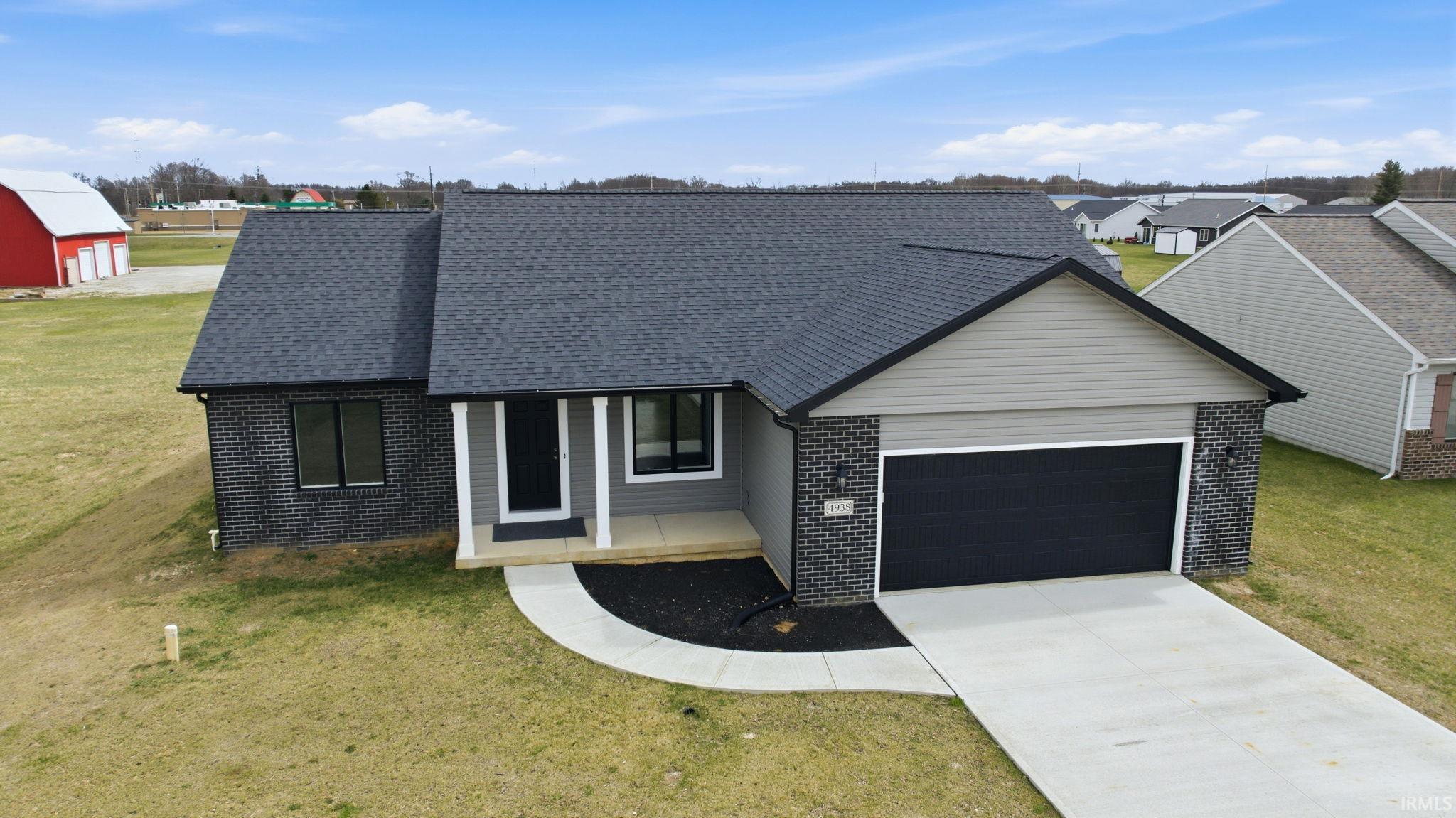 View of front of property featuring a front yard, brick siding, driveway, an attached garage, and a porch