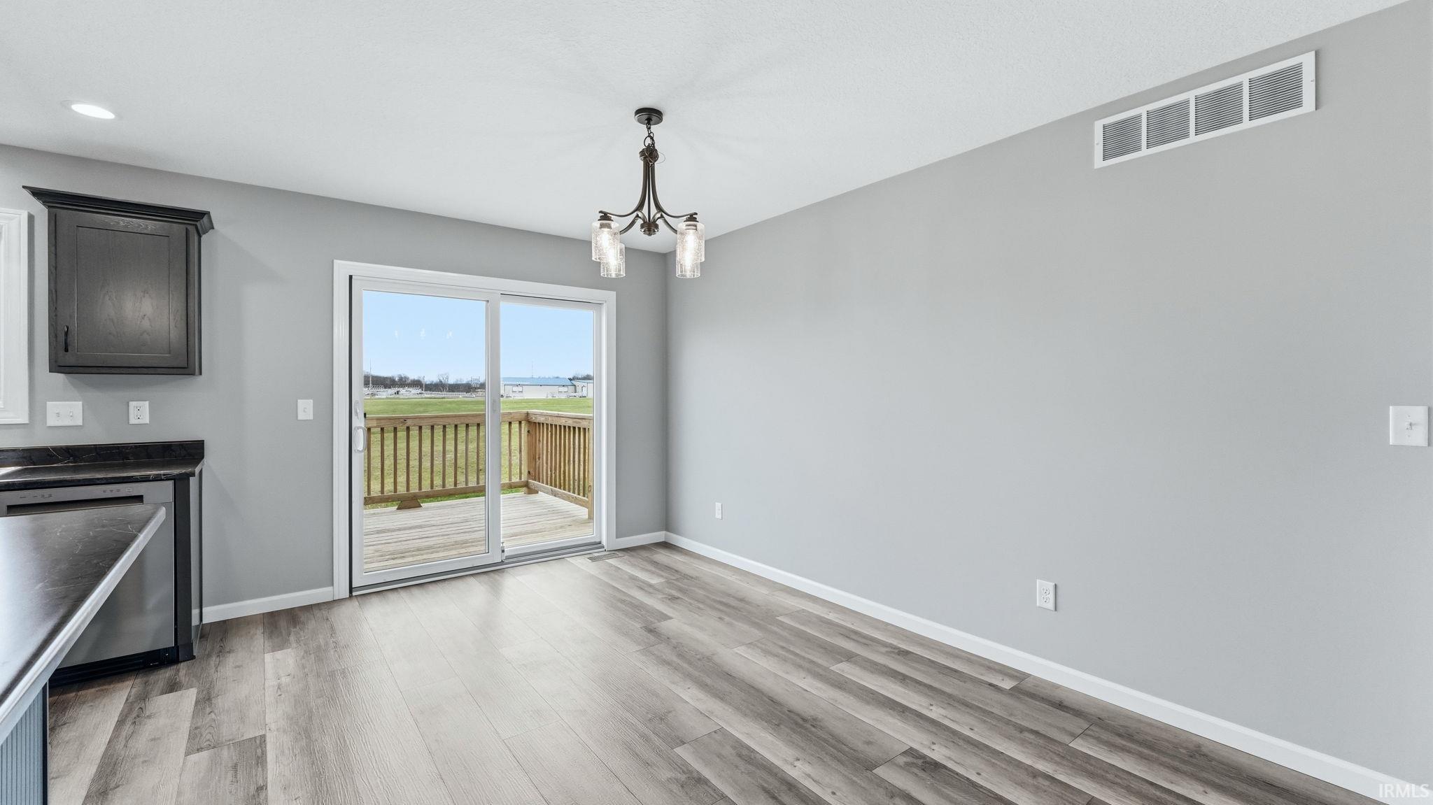 Unfurnished dining area featuring suspended lighting and light wood-style flooring