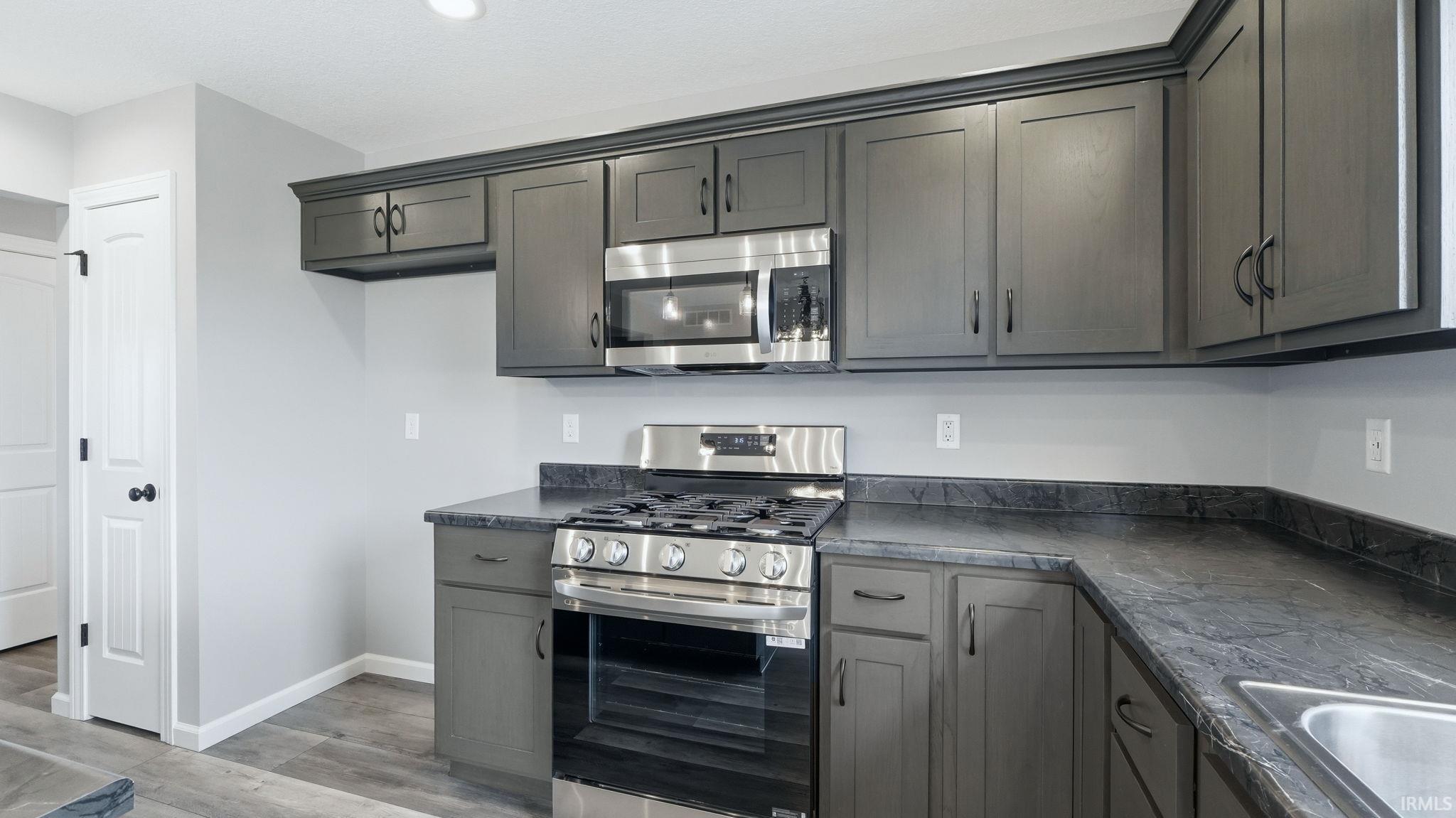 Kitchen featuring dark countertops, stainless steel appliances, light wood-type flooring, and gray cabinetry