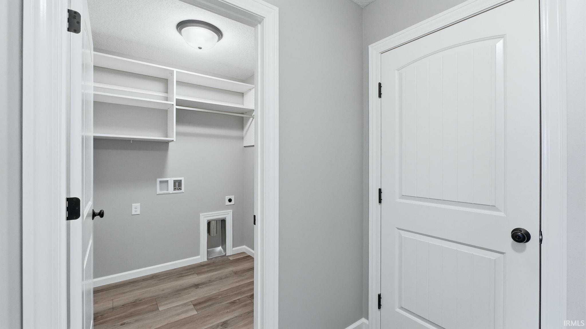 Laundry area with light wood-style flooring, electric dryer hookup, and washer hookup