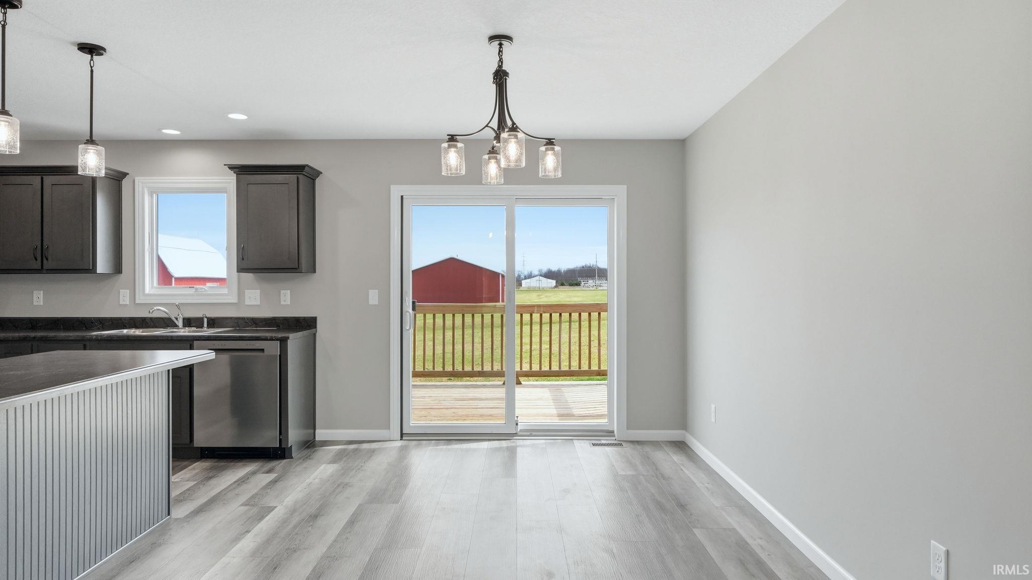 Kitchen featuring dark countertops, a chandelier, stainless steel dishwasher, and light wood-style floors