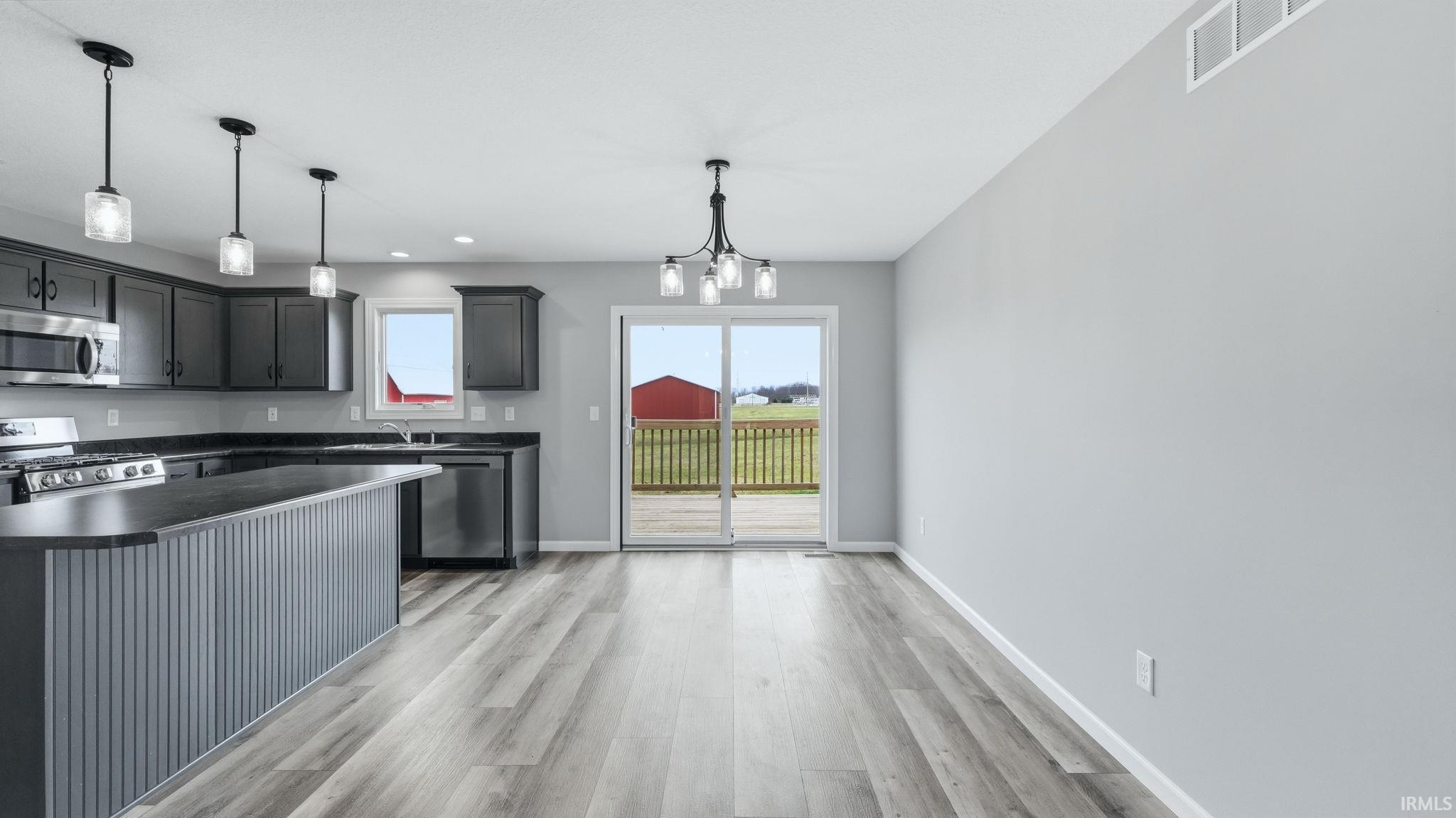 Kitchen featuring dark countertops, a chandelier, light wood-style flooring, and stainless steel appliances
