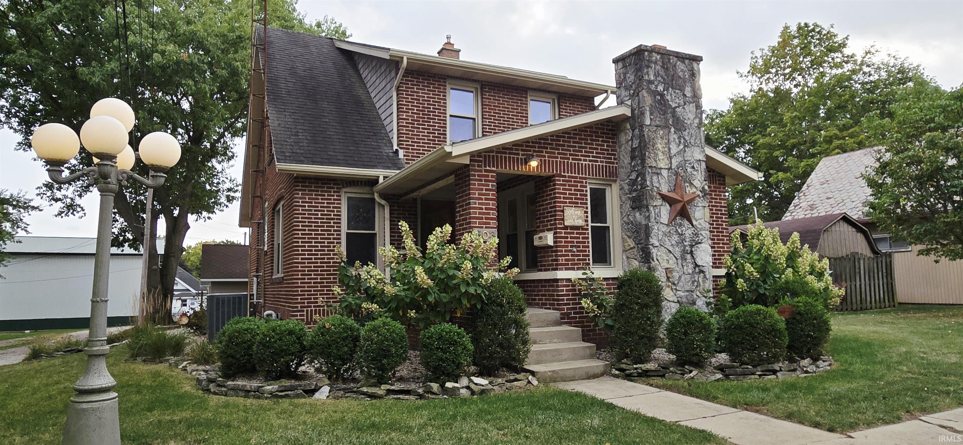View of front of house with brick siding, roof with shingles, and a chimney