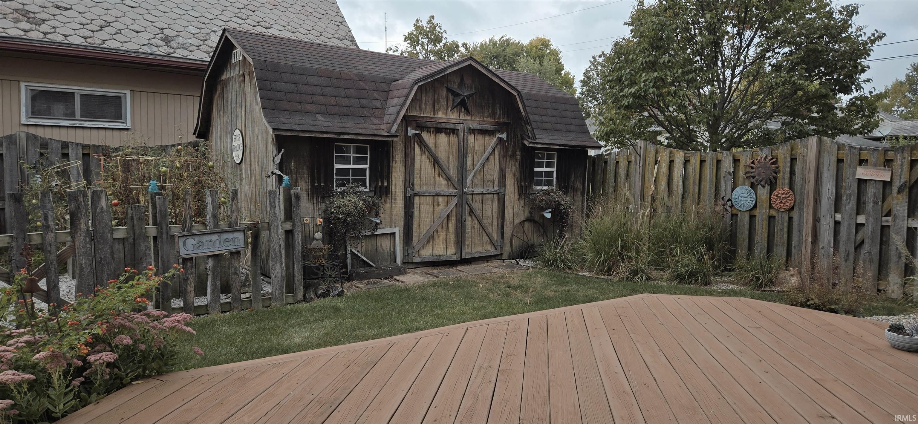 Wooden terrace with a storage shed and a fenced backyard