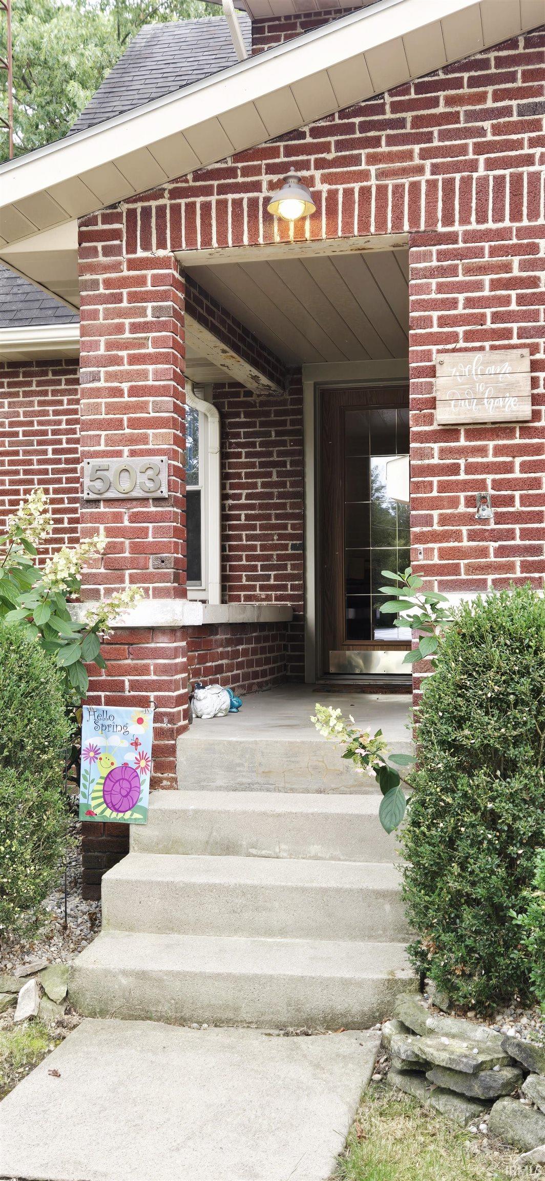 Entrance to property with brick siding and a shingled roof