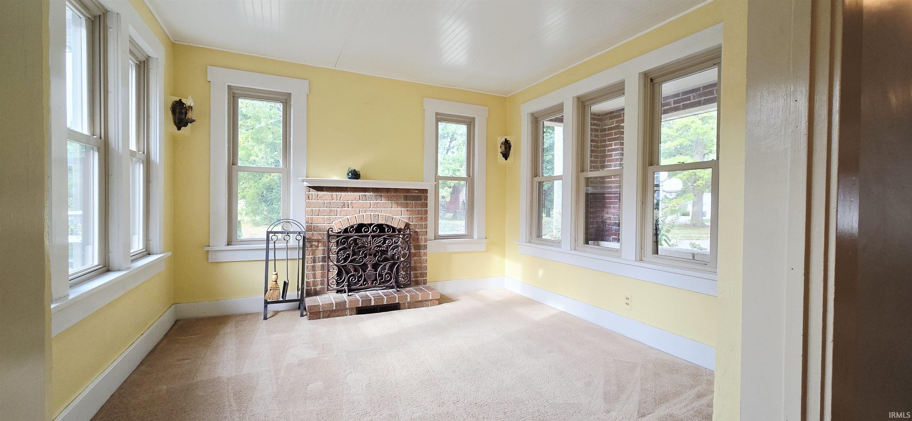 Unfurnished living room with a fireplace, carpet, and plenty of natural light