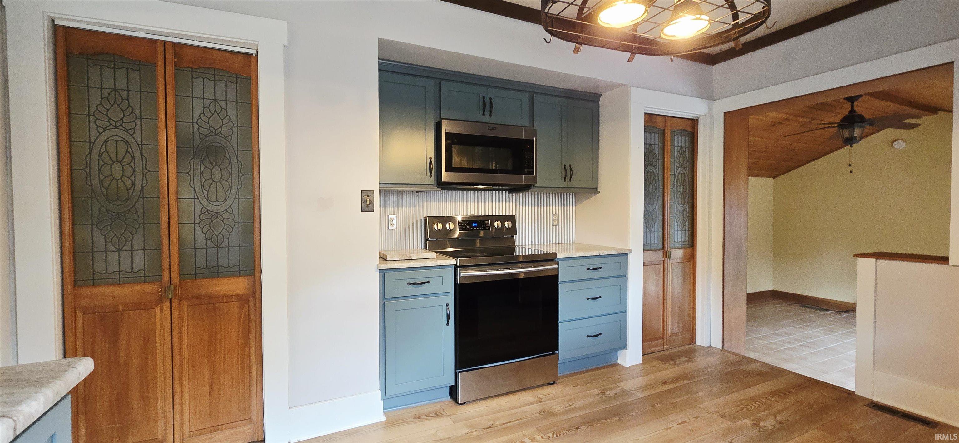Kitchen featuring stainless steel appliances, light wood finished floors, a ceiling fan, and lofted ceiling