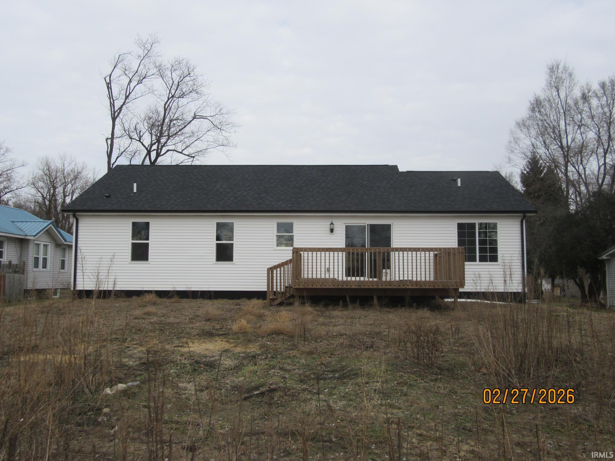 Rear view of property featuring a deck and roof with shingles