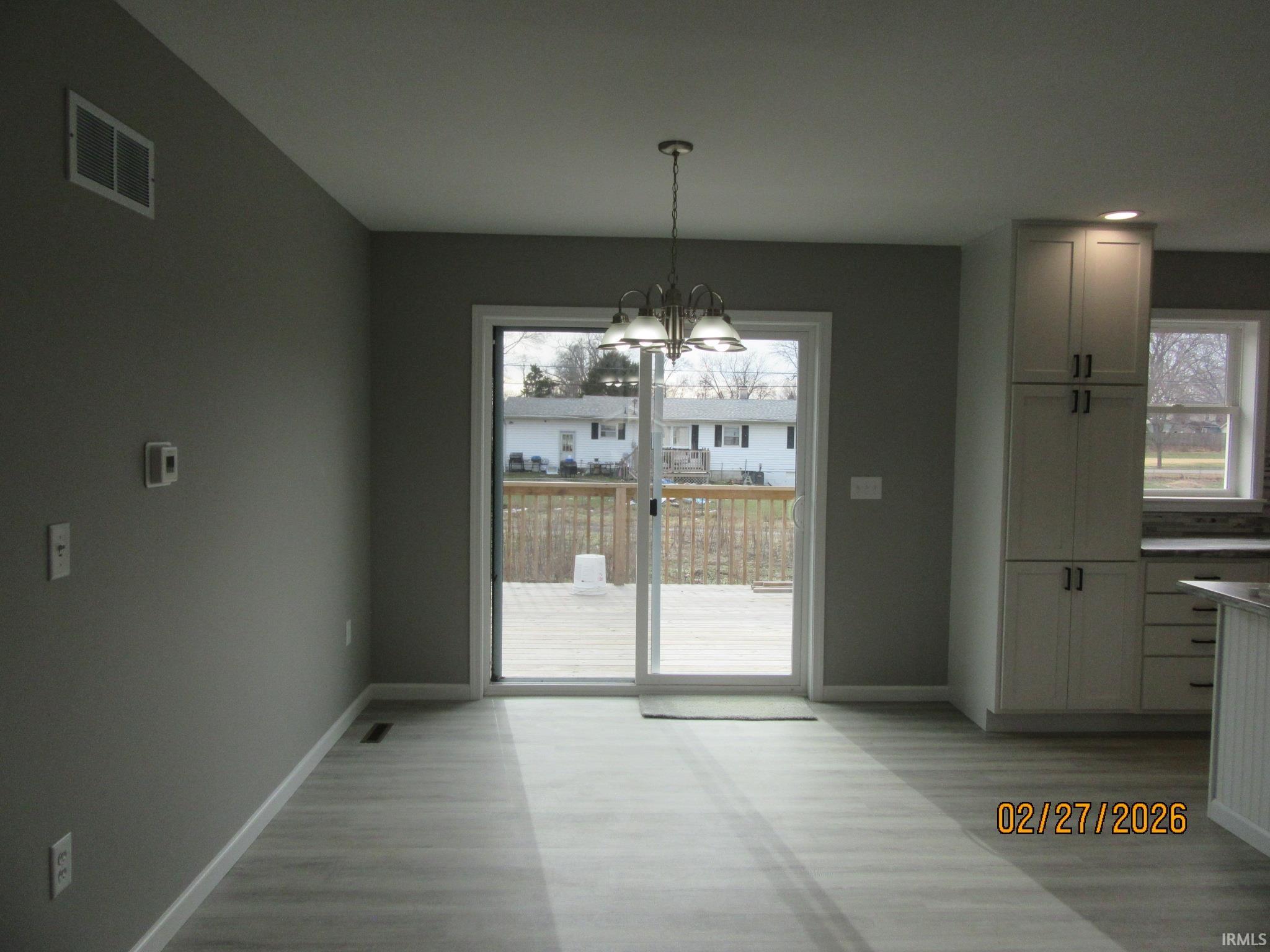 Unfurnished dining area with a chandelier, light wood finished floors, and healthy amount of natural light