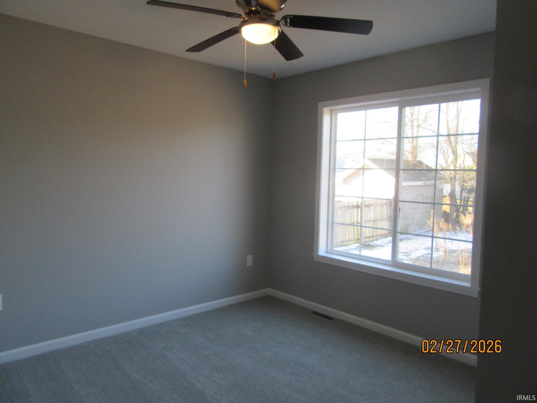 Empty room featuring a ceiling fan and carpet