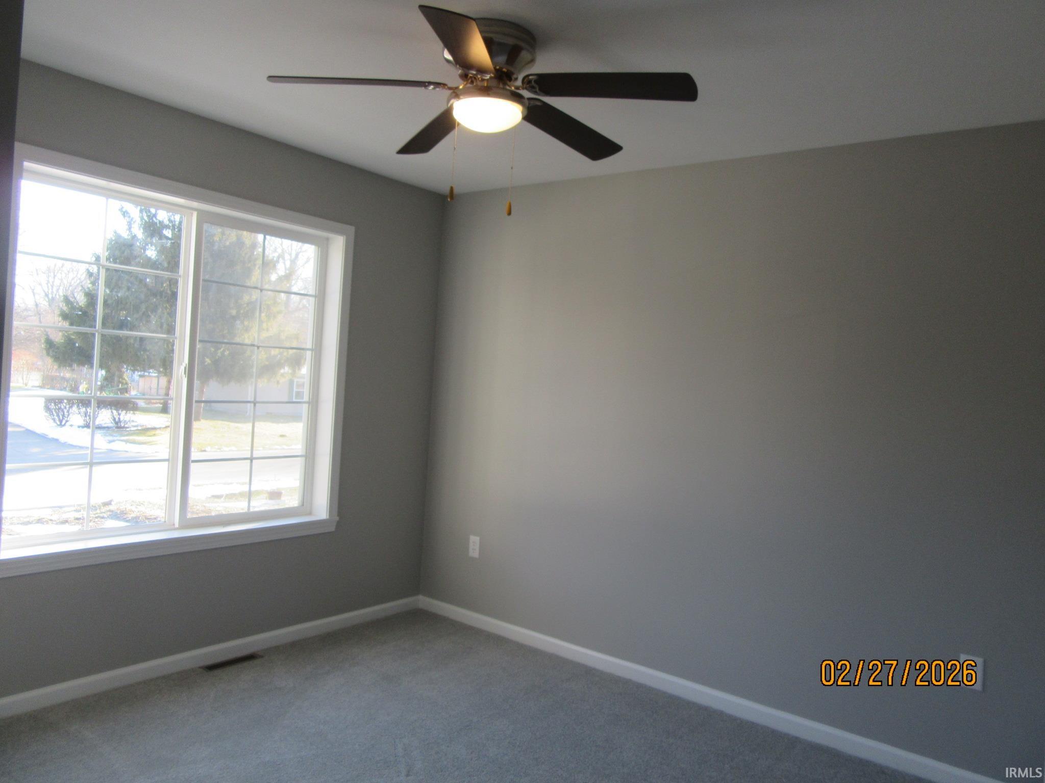 Empty room with light colored carpet and ceiling fan