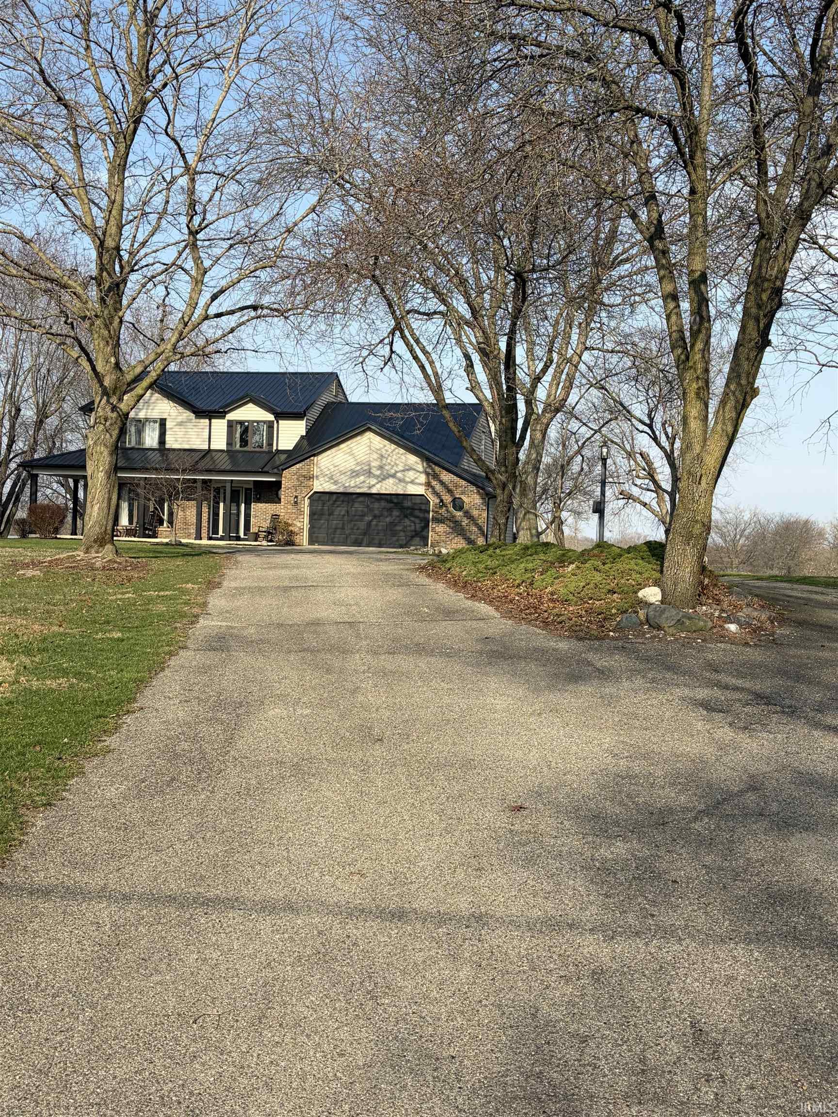 View of front of house featuring a garage, driveway, covered porch, and a front yard