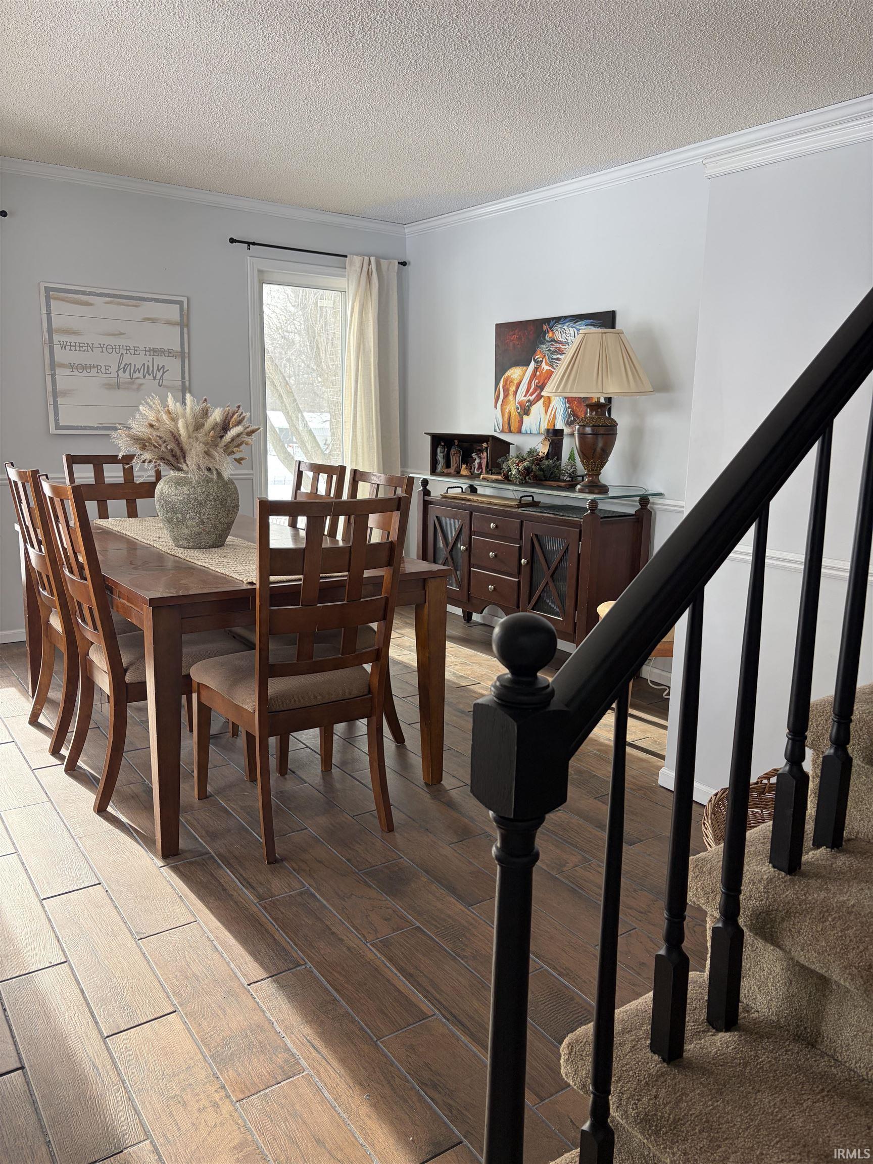 Dining space with ornamental molding, a textured ceiling, and wood tiled floors