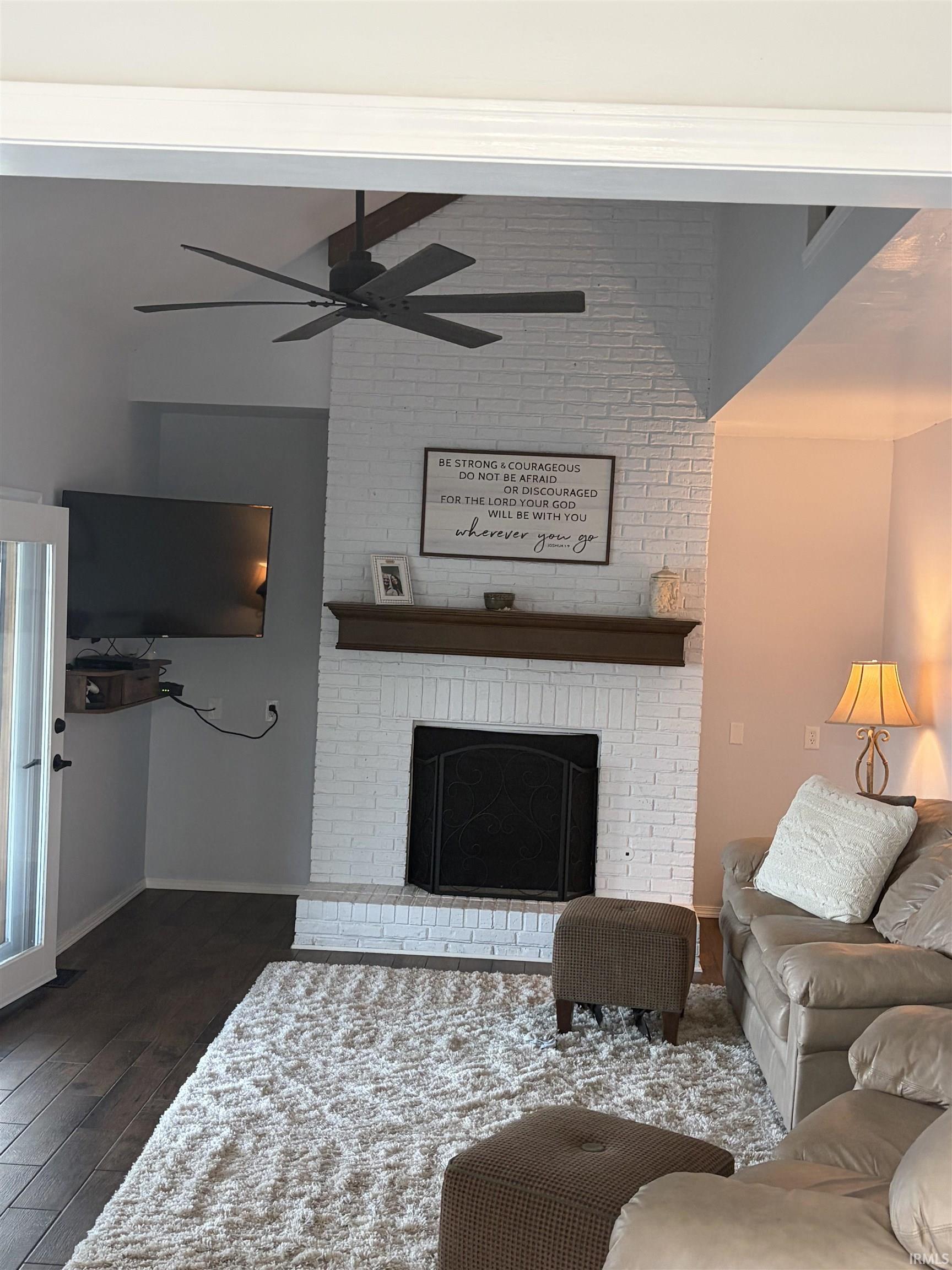 Living area featuring hardwood / wood-style flooring, ceiling fan, a fireplace, and vaulted ceiling