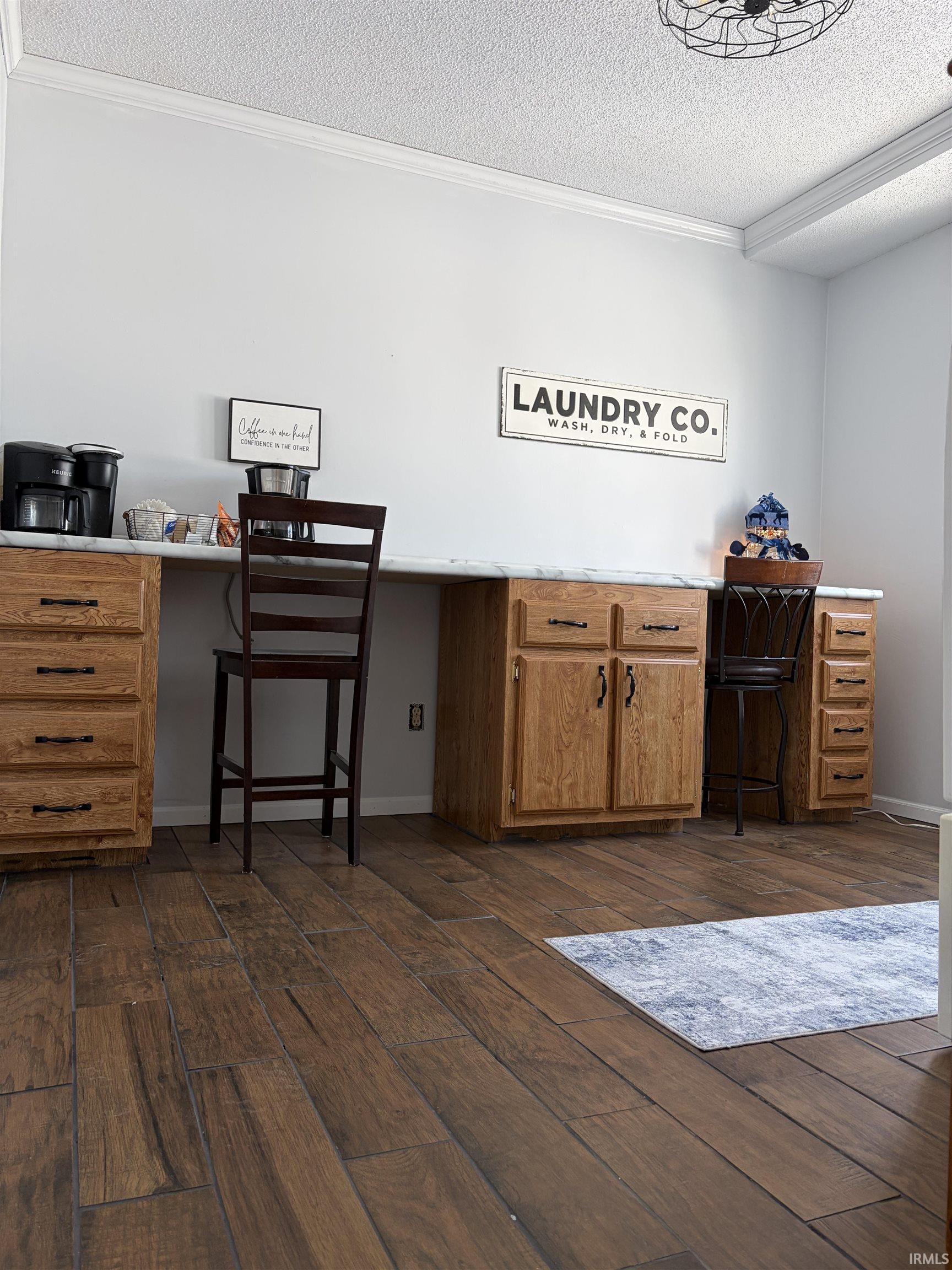 Bar with crown molding, light countertops, a textured ceiling, dark wood-type flooring, and brown cabinetry