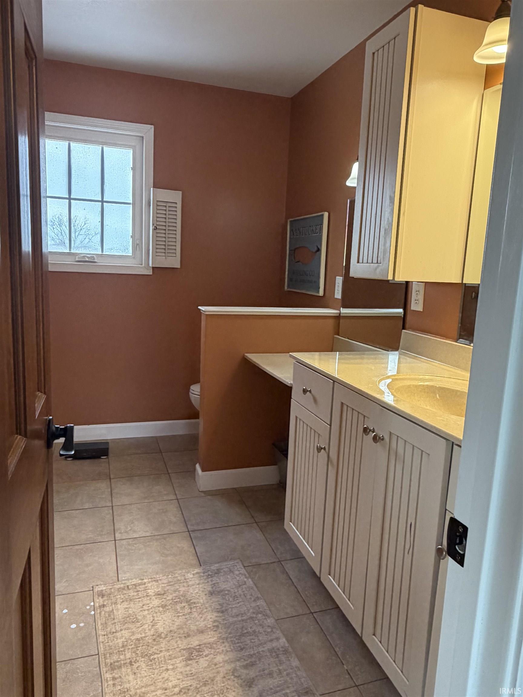 Bathroom with light tile patterned floors and vanity