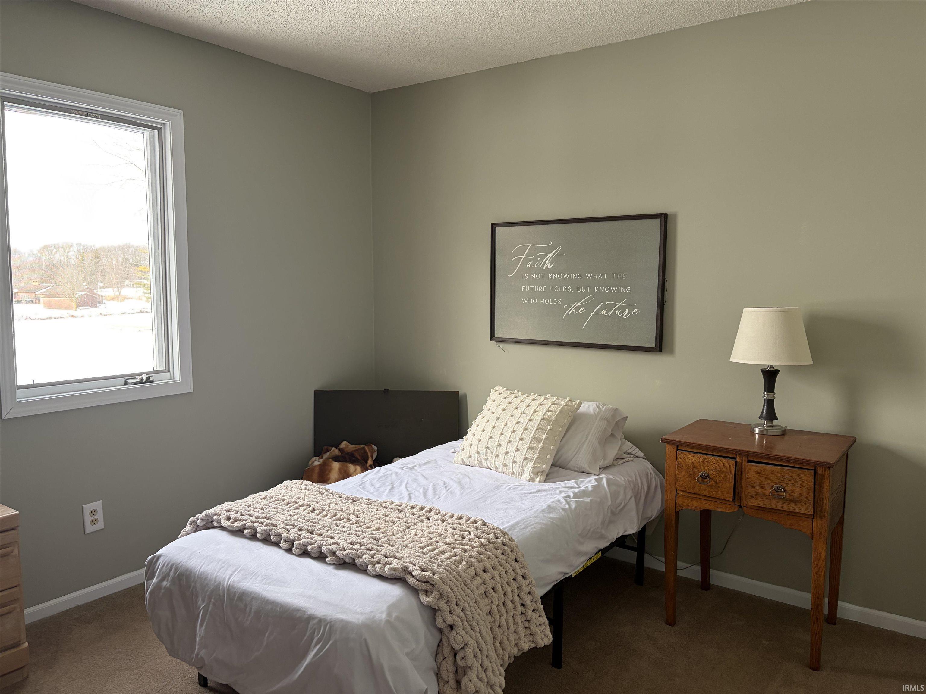 Carpeted bedroom featuring a textured ceiling and baseboards