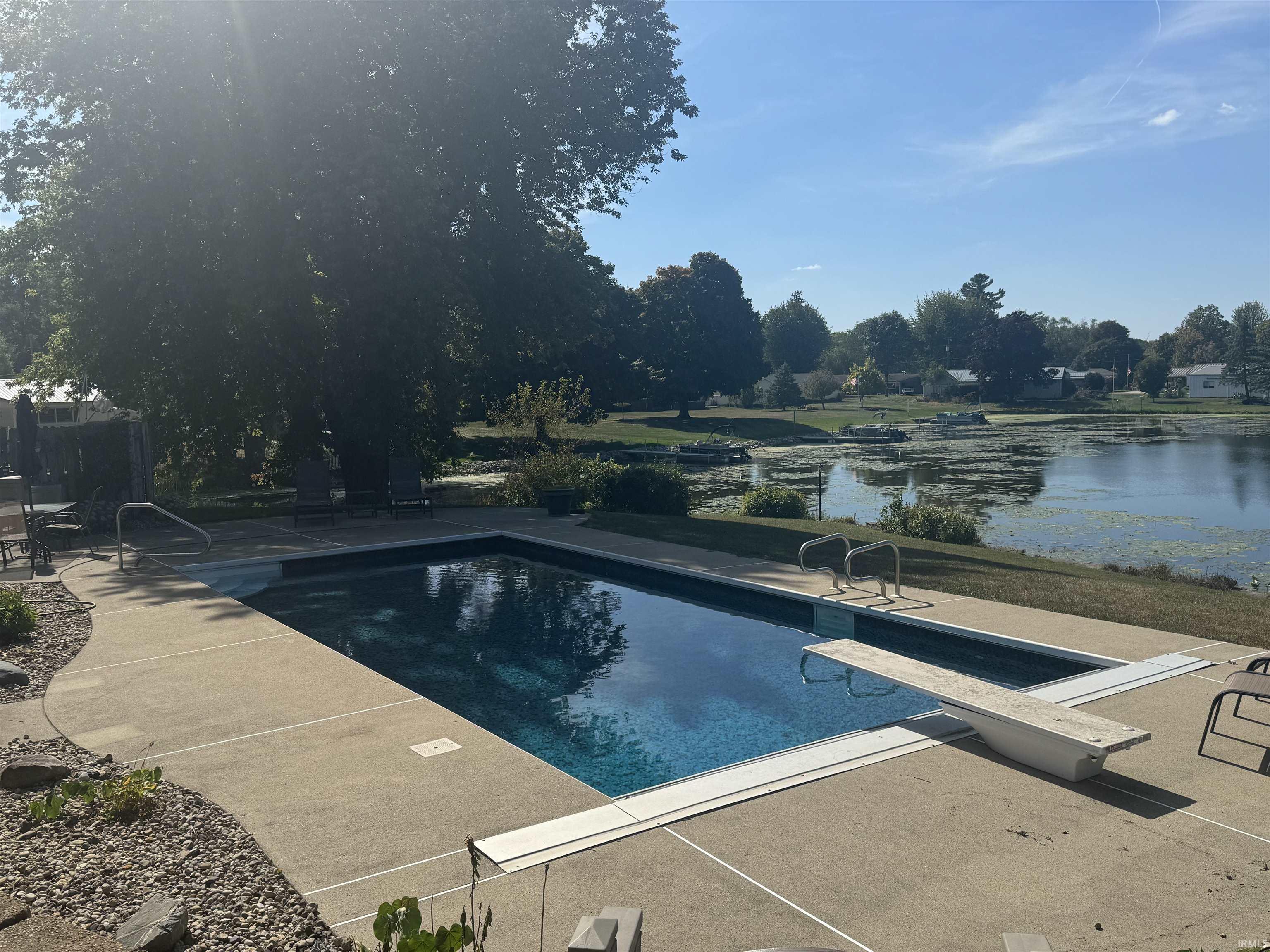 Outdoor pool featuring a diving board, a water view, and a patio area