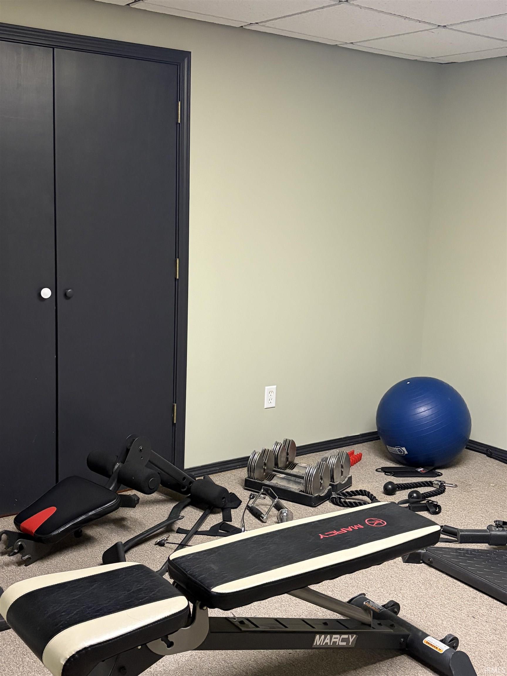 Exercise area featuring a drop ceiling and baseboards