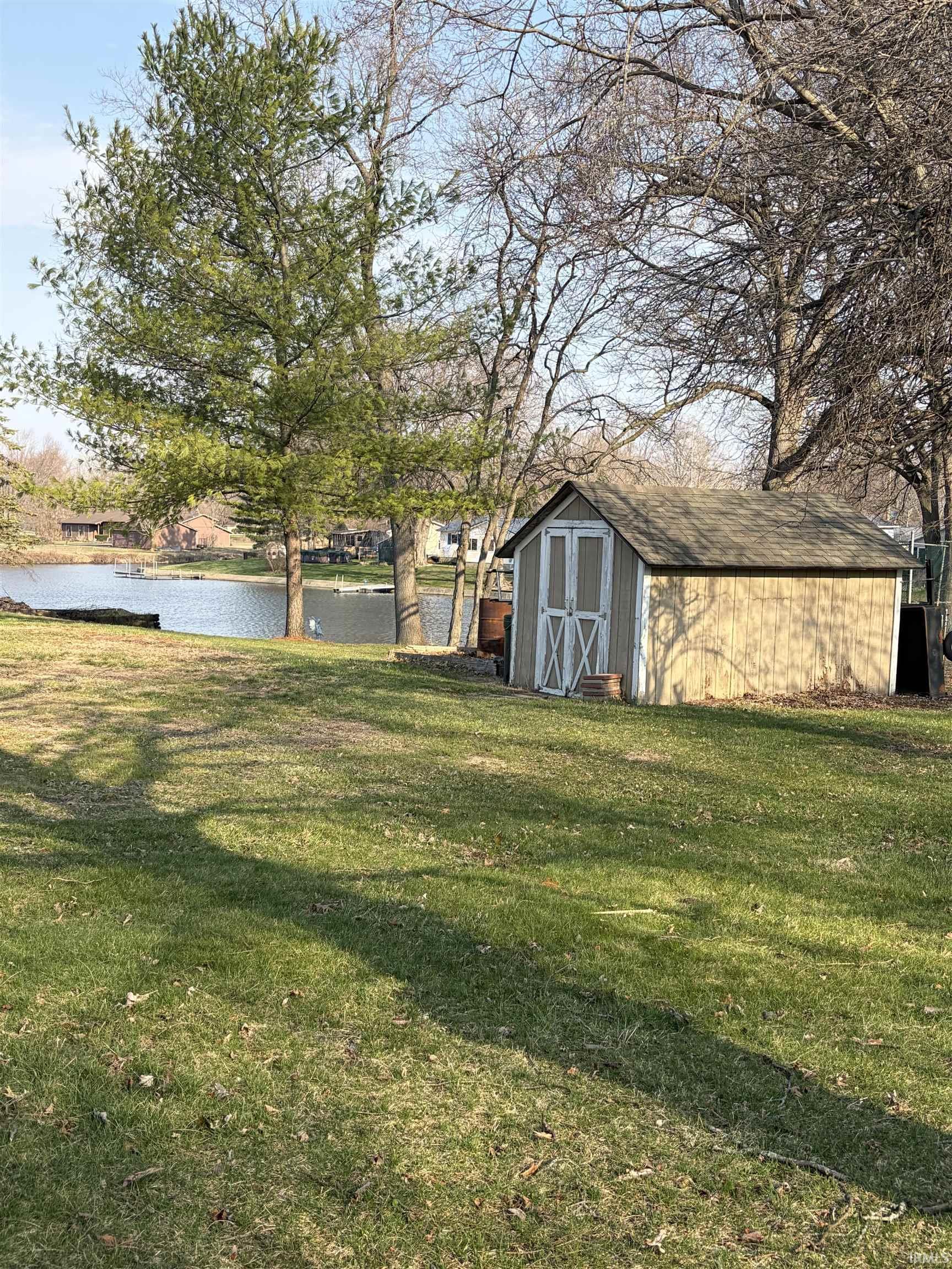View of green lawn with a shed and a water view