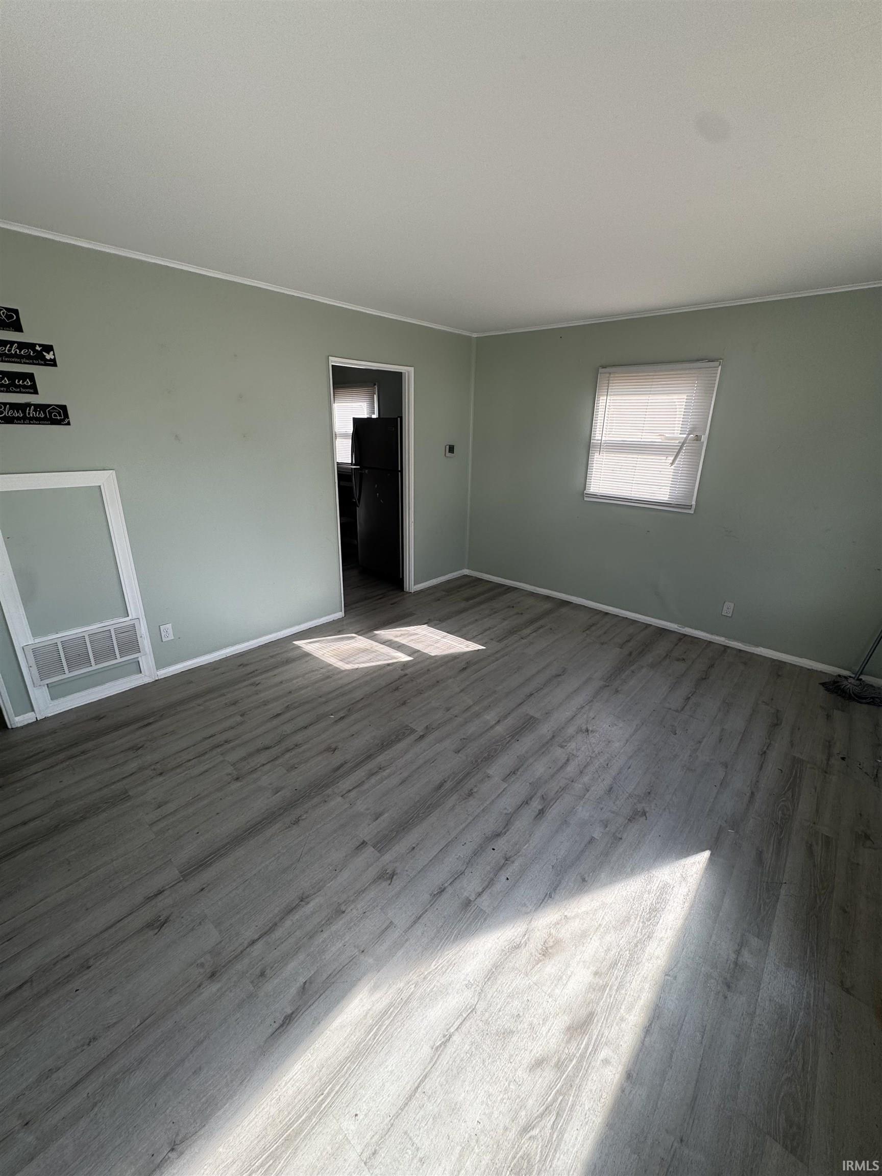 Unfurnished living room with wood finished floors and crown molding