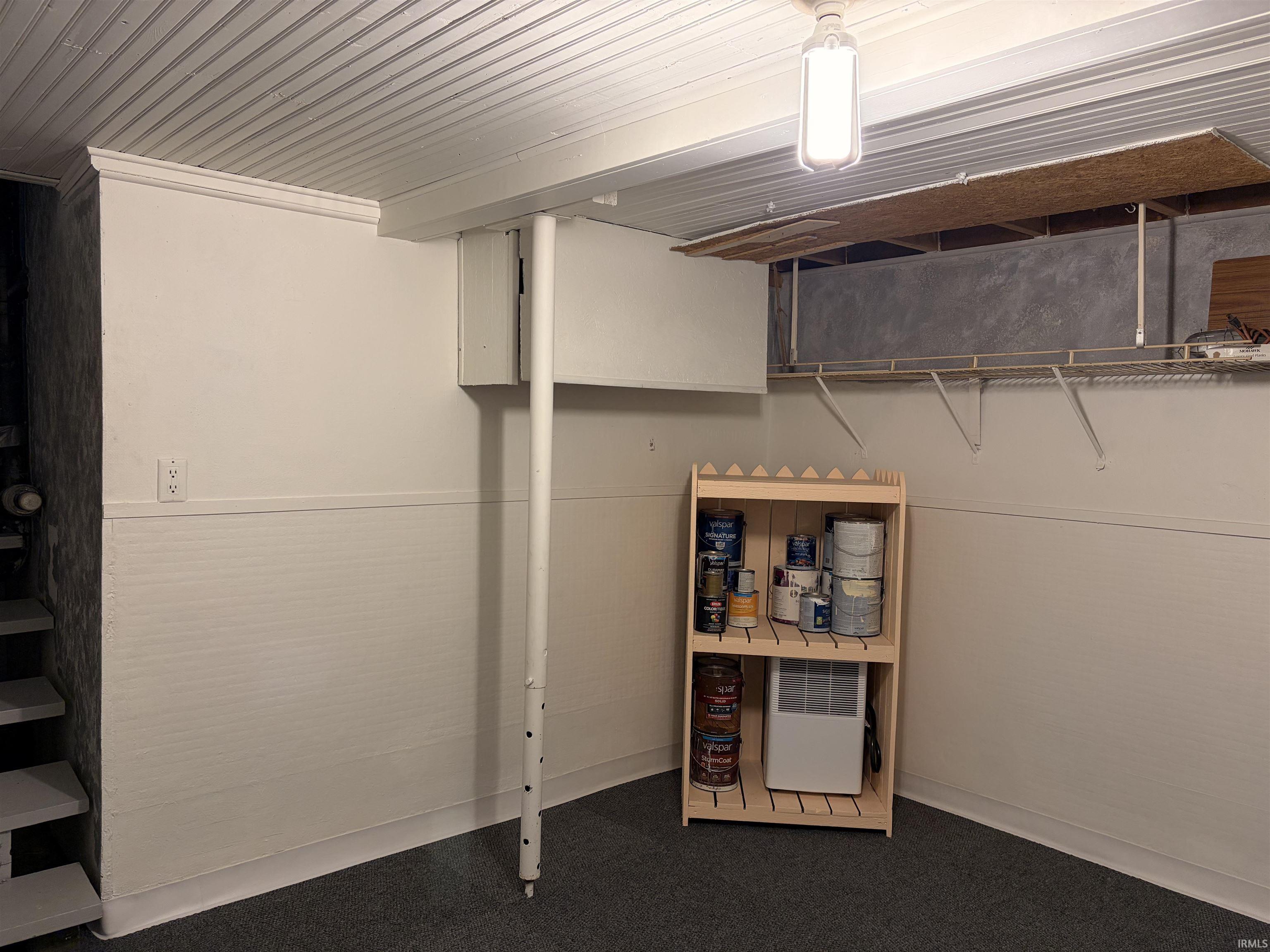 Finished basement area with covered storage shelving.