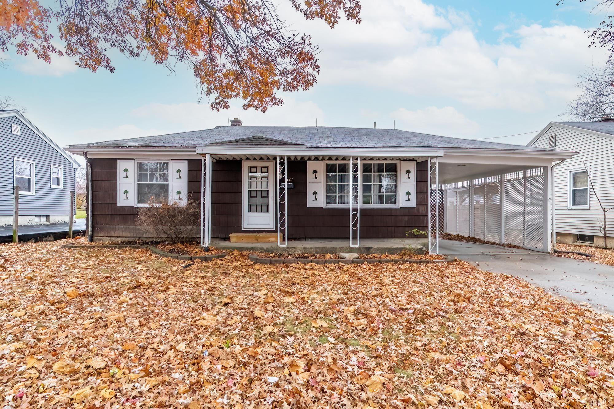View of front of home with a carport, driveway, covered porch, and roof with shingles