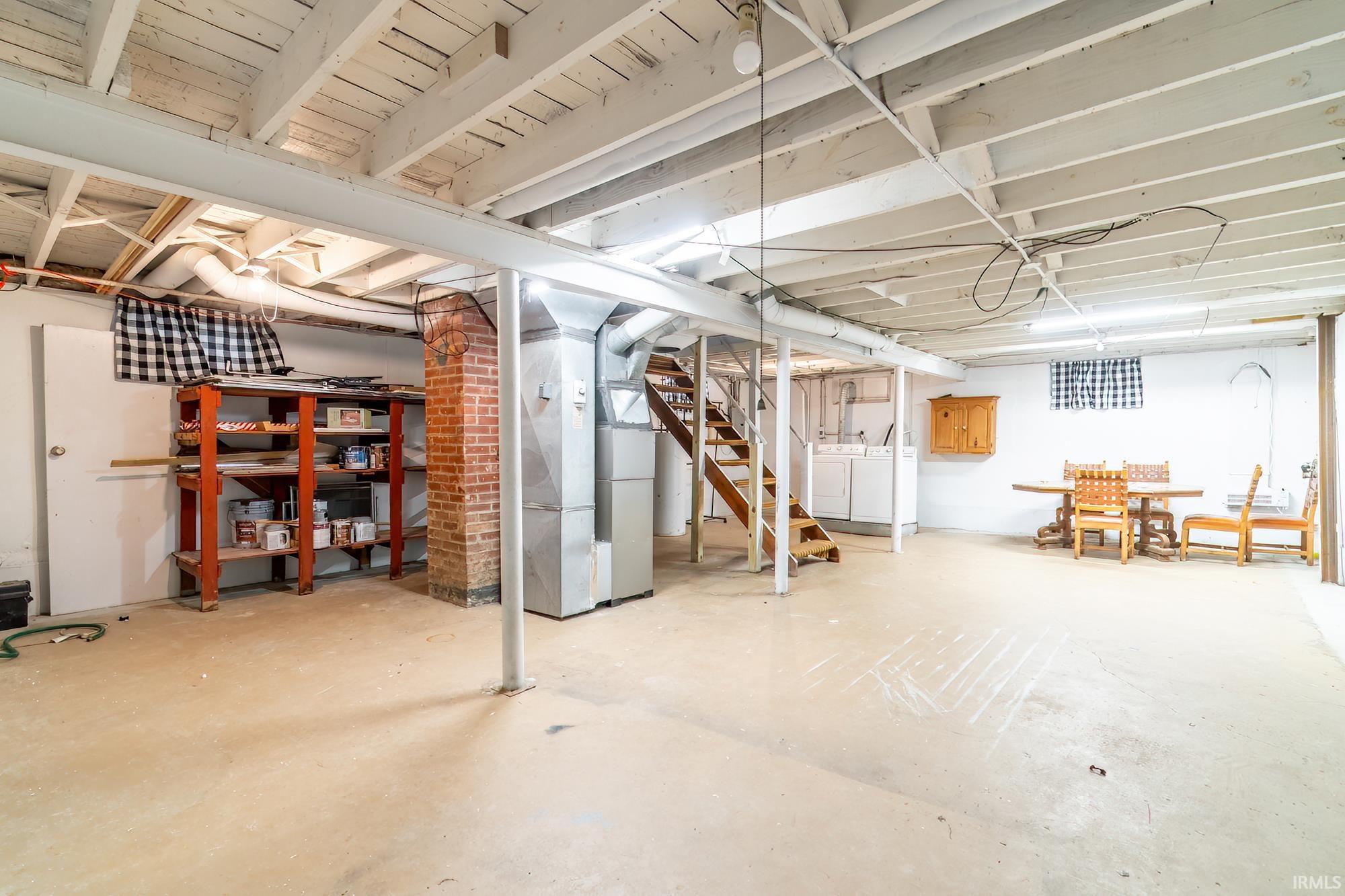 Unfinished basement with heating unit and washer and clothes dryer