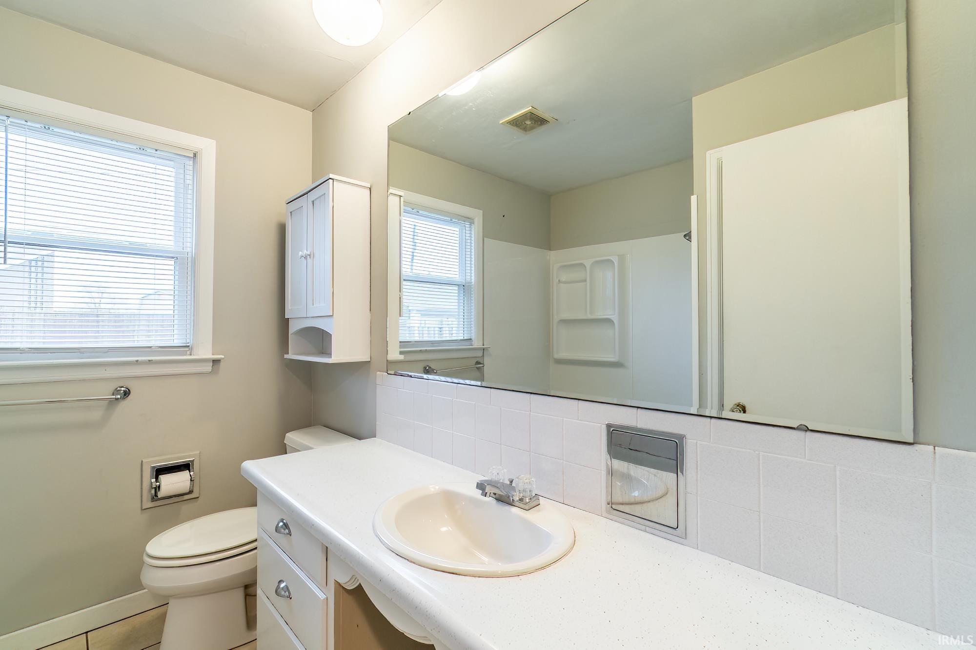 Full bath with vanity, backsplash, a shower, and tile patterned floors