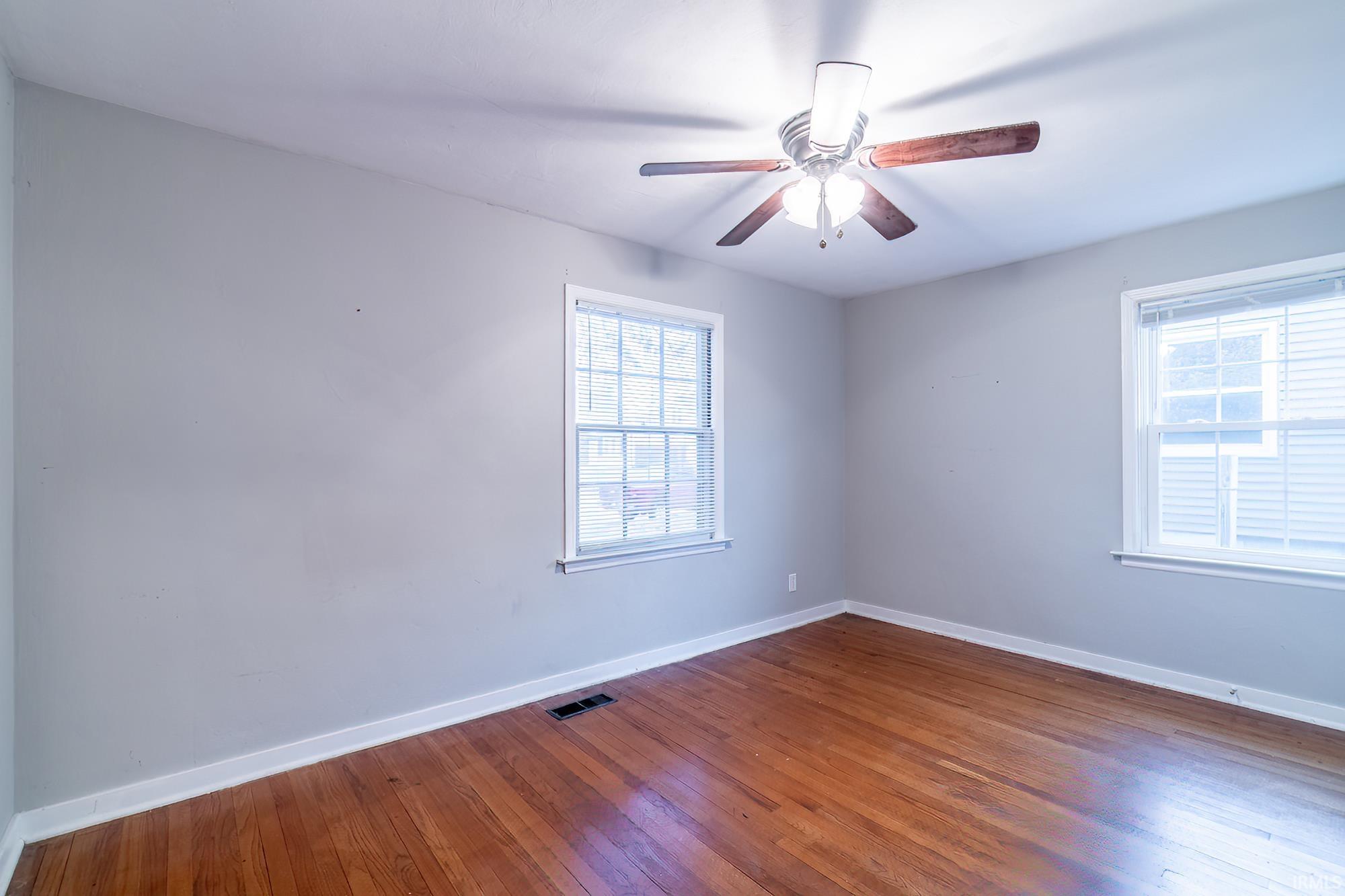 Unfurnished room with dark wood finished floors and ceiling fan