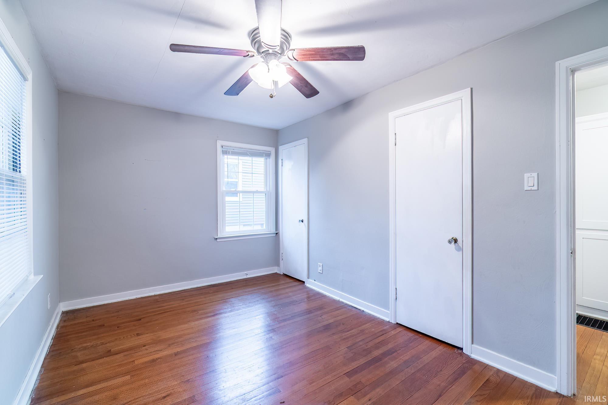 Unfurnished bedroom with dark wood-style floors, a ceiling fan, and a closet