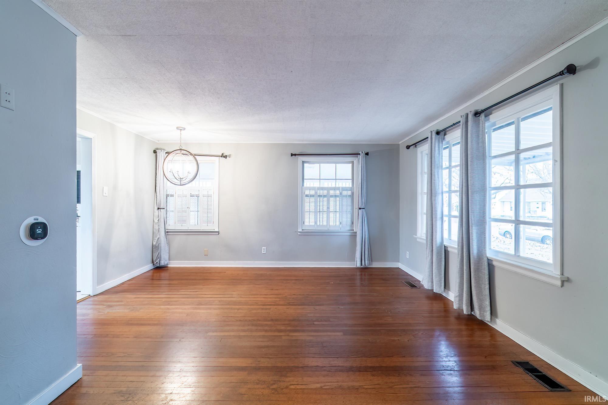 Unfurnished room with dark wood finished floors, a chandelier, and a textured ceiling