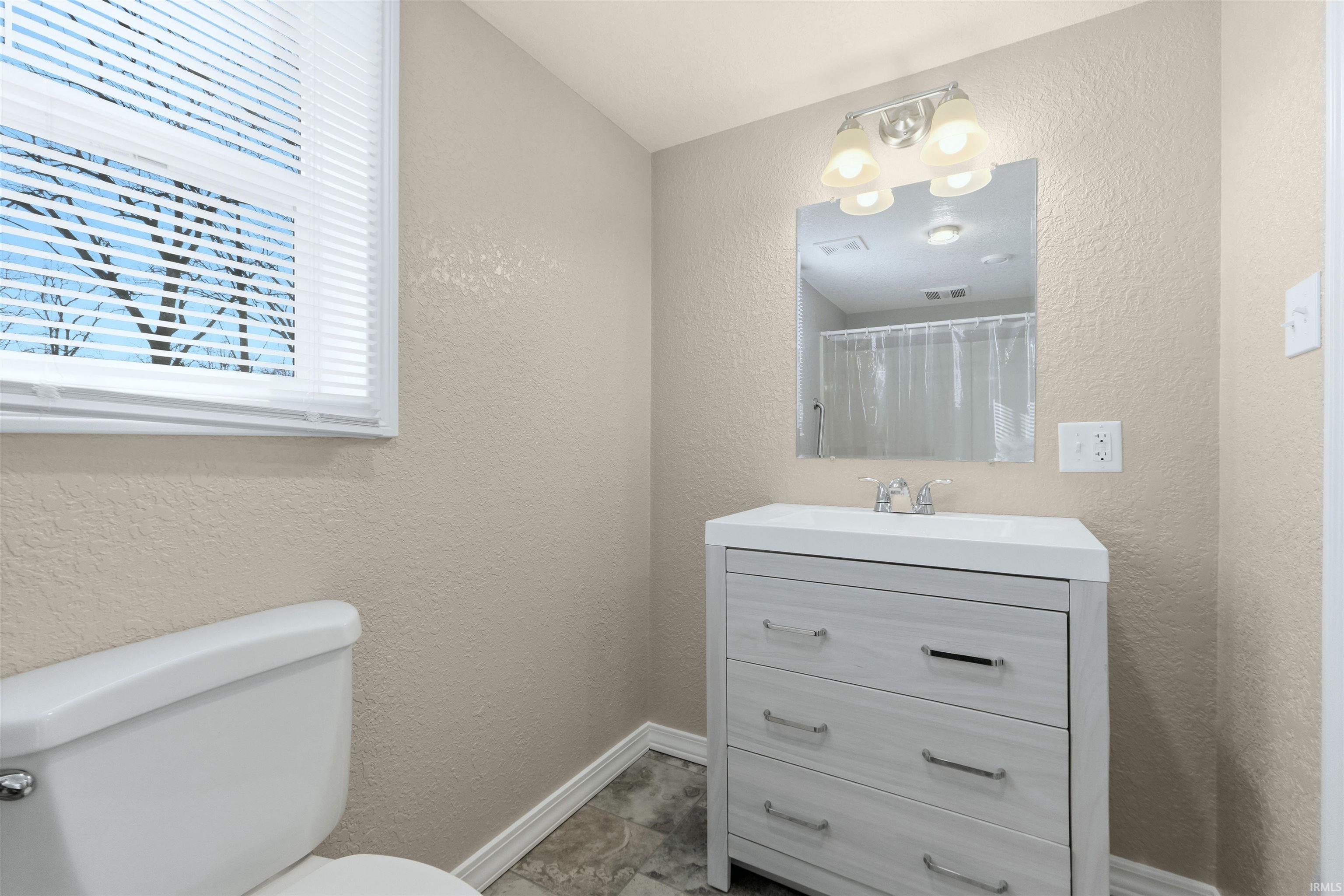 Full bathroom with a textured wall, vanity, and a shower with shower curtain