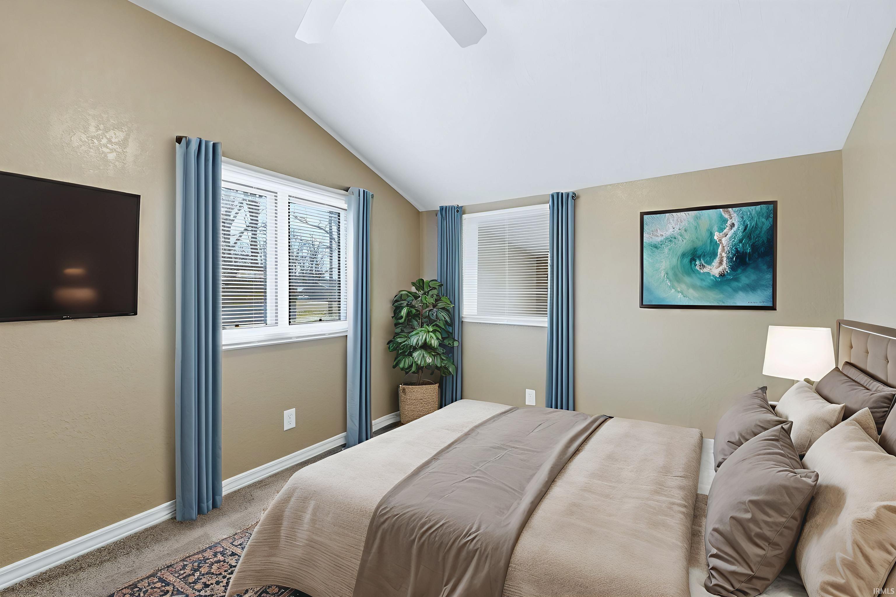 Carpeted bedroom with vaulted ceiling and ceiling fan