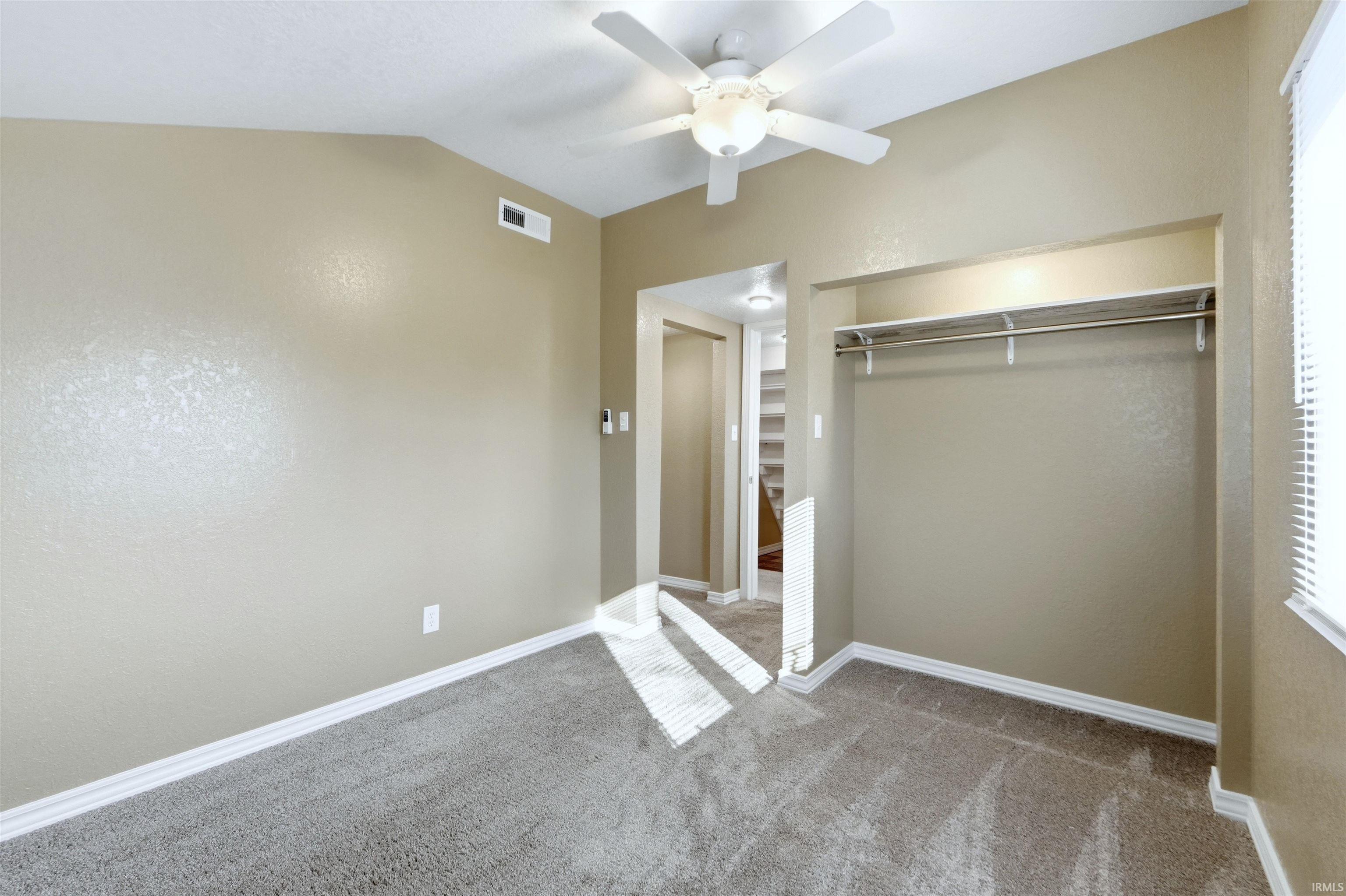 Unfurnished bedroom with light colored carpet, a closet, a ceiling fan, and vaulted ceiling