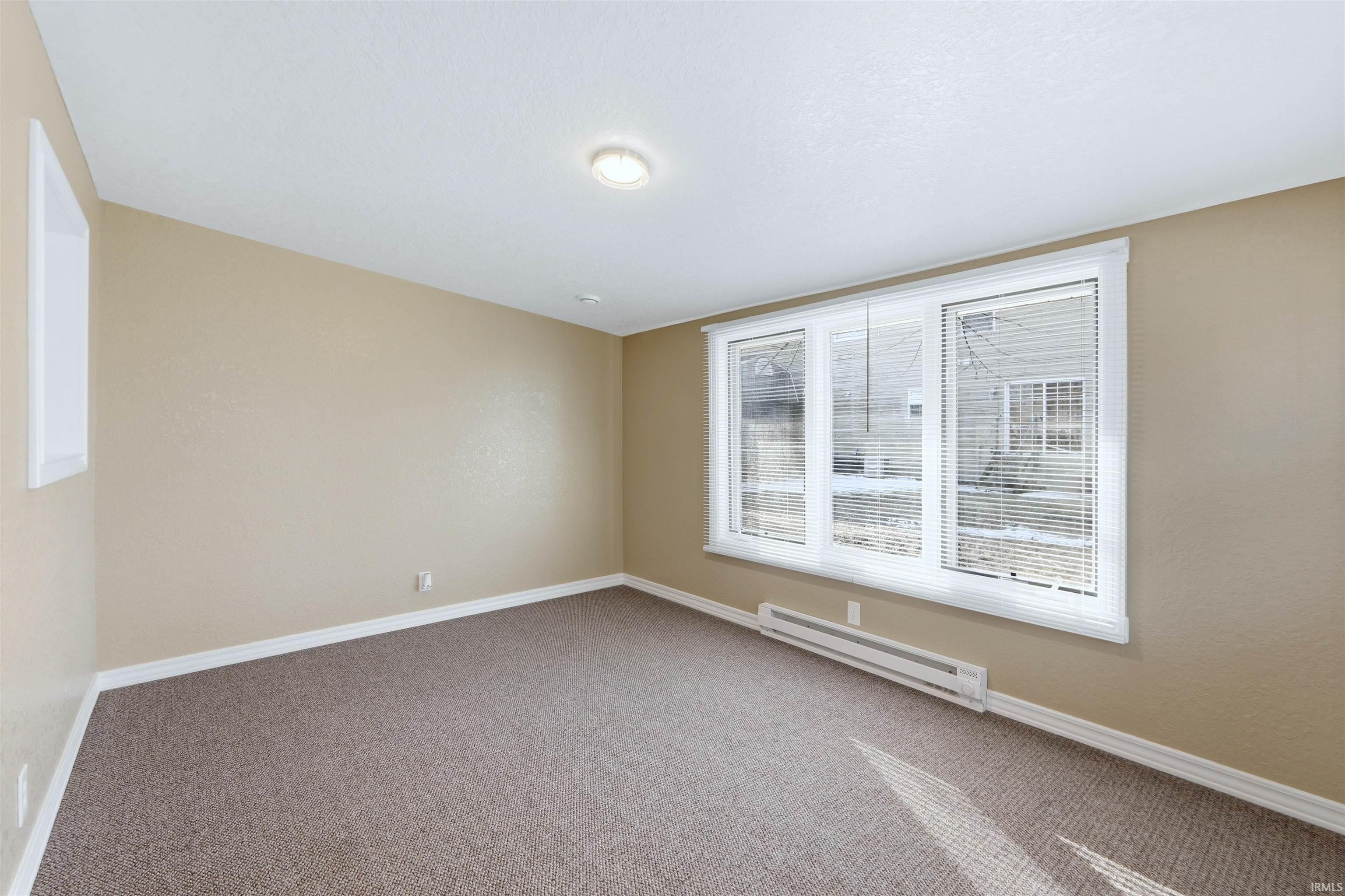 Empty room with baseboard heating and carpet flooring