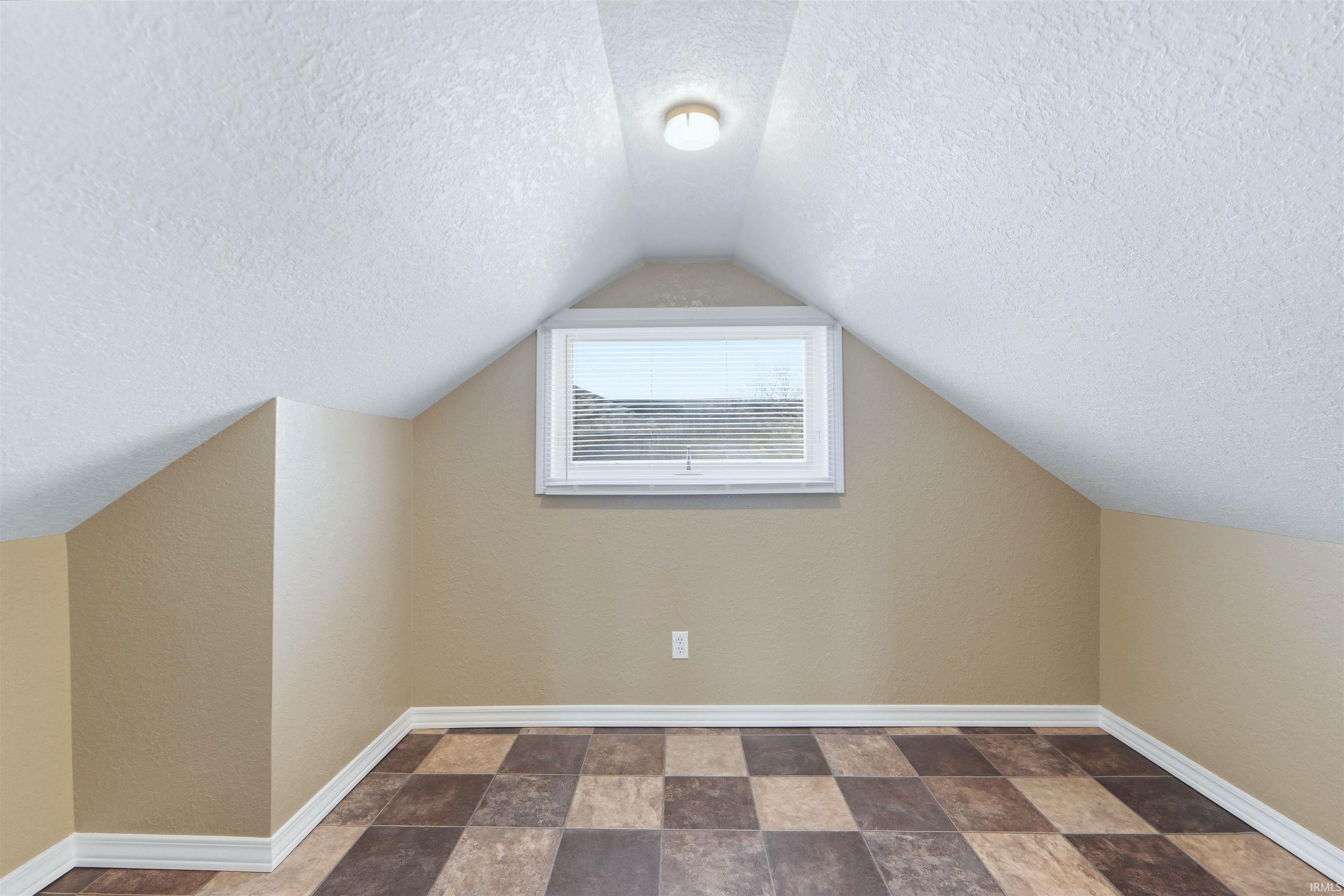 Bonus room featuring stone finish floors and a textured ceiling