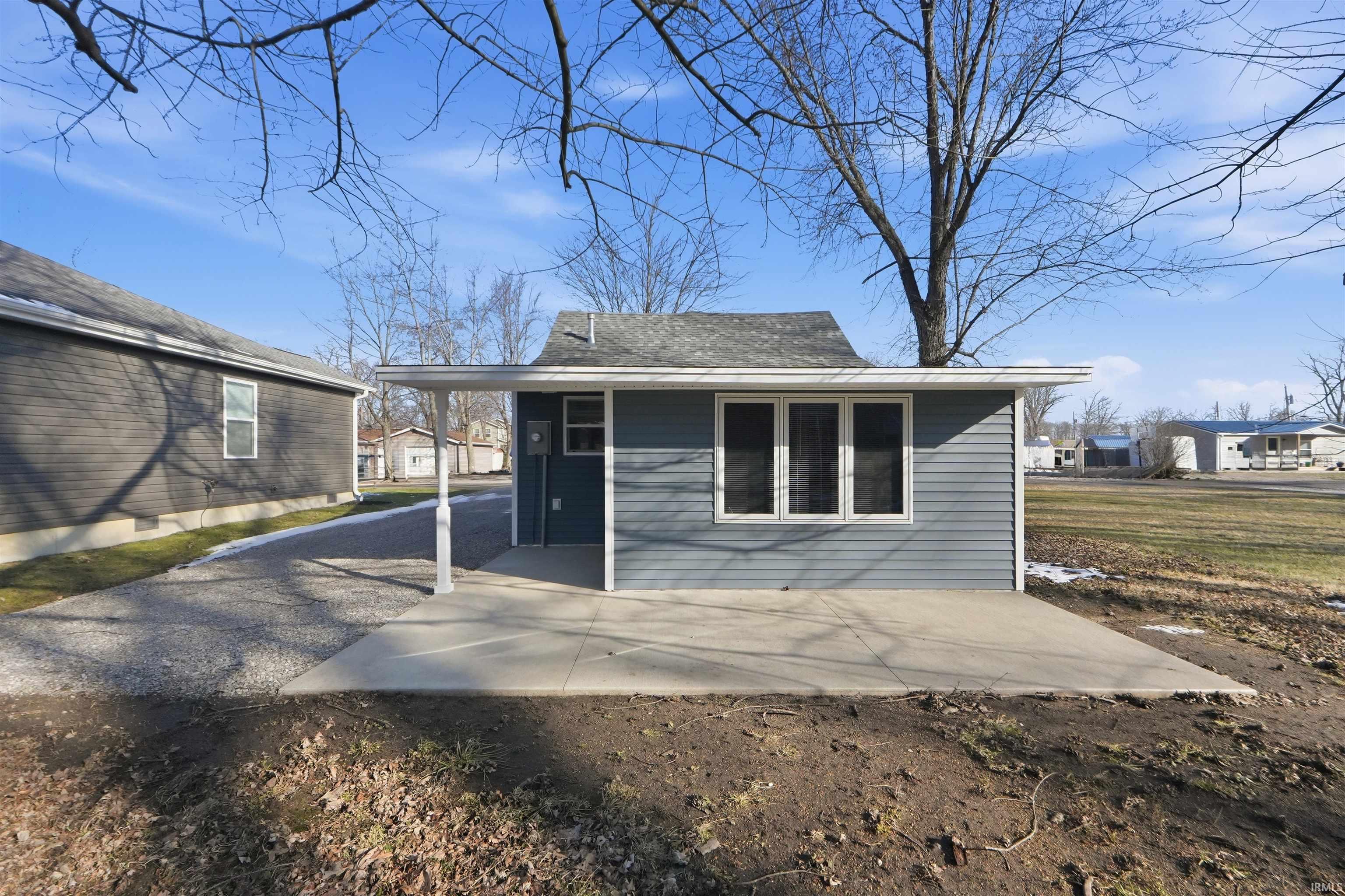 Rear view of house featuring a patio area, asphalt driveway, and a carport