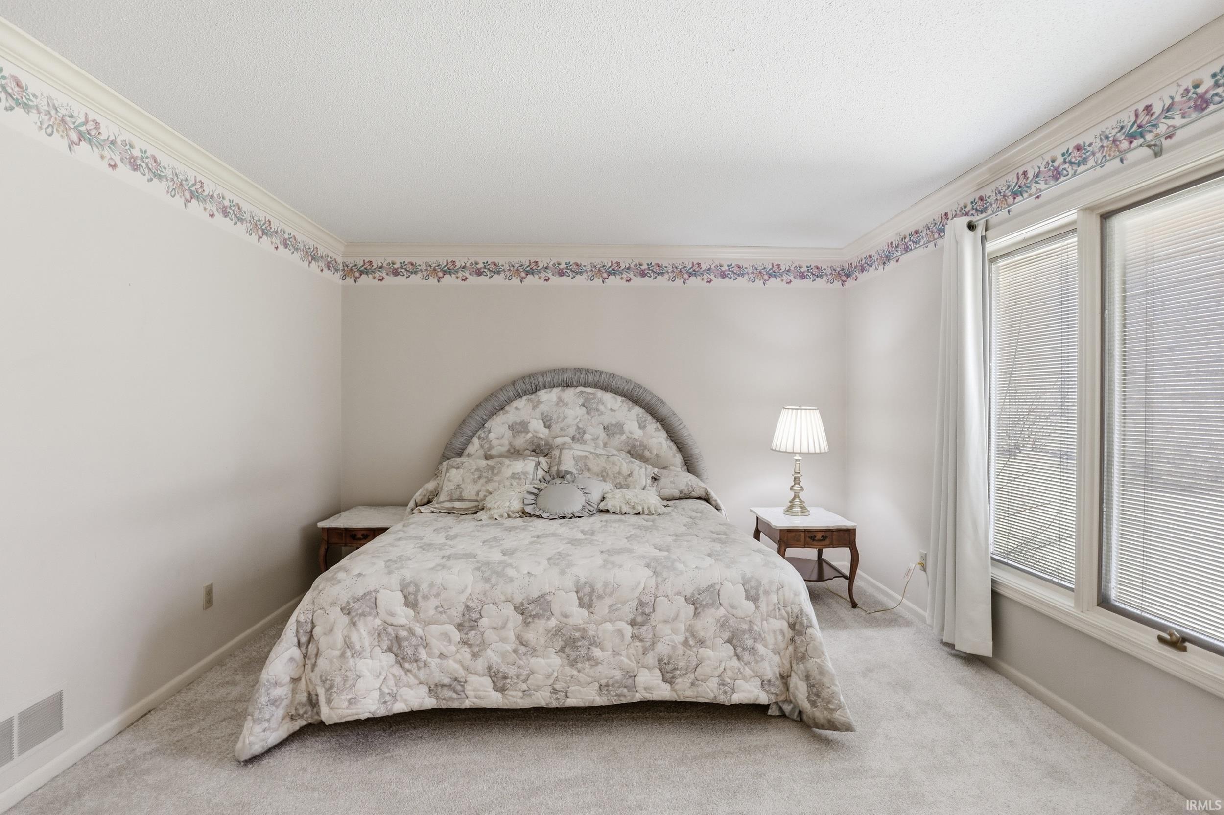 Bedroom with crown molding and light colored carpet