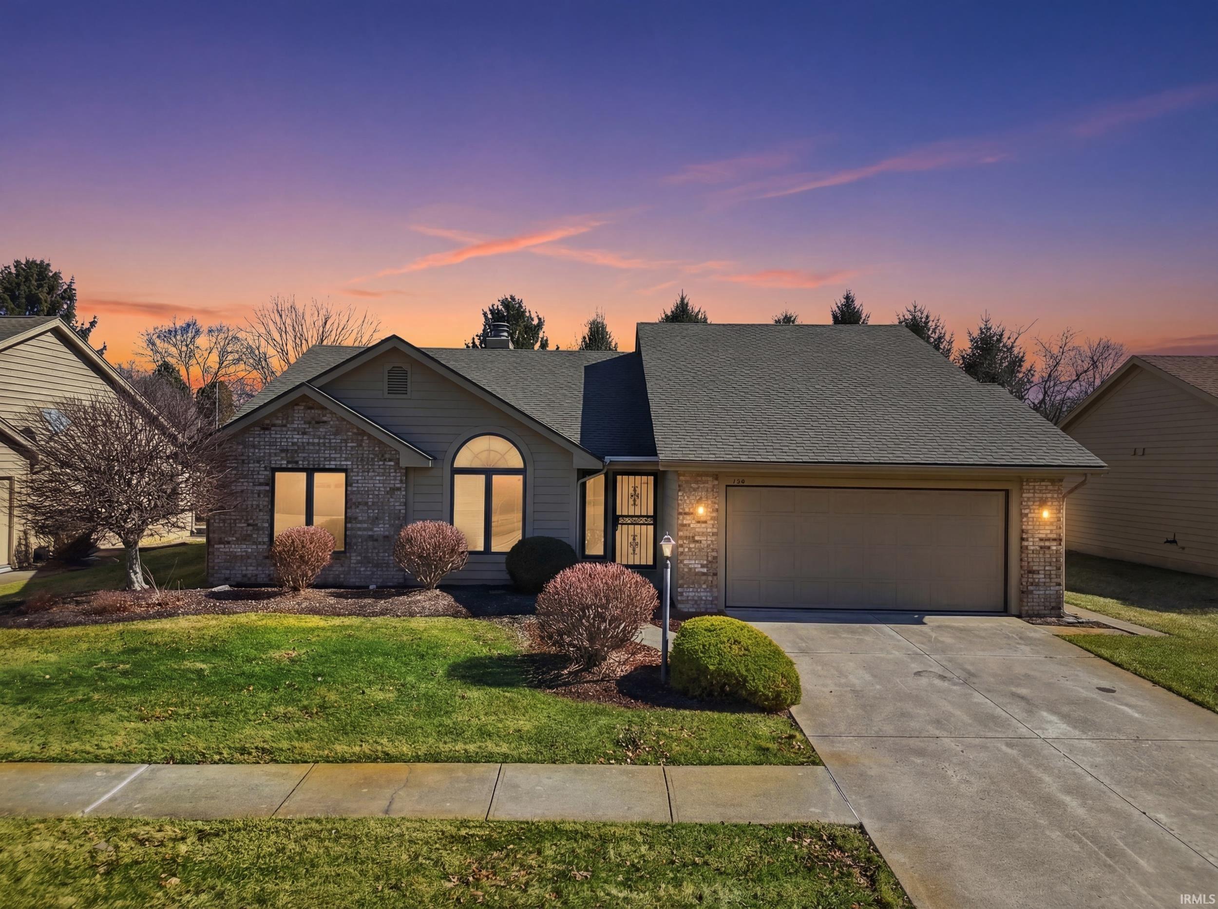 View of front facade featuring brick siding, roof with shingles, and a garage