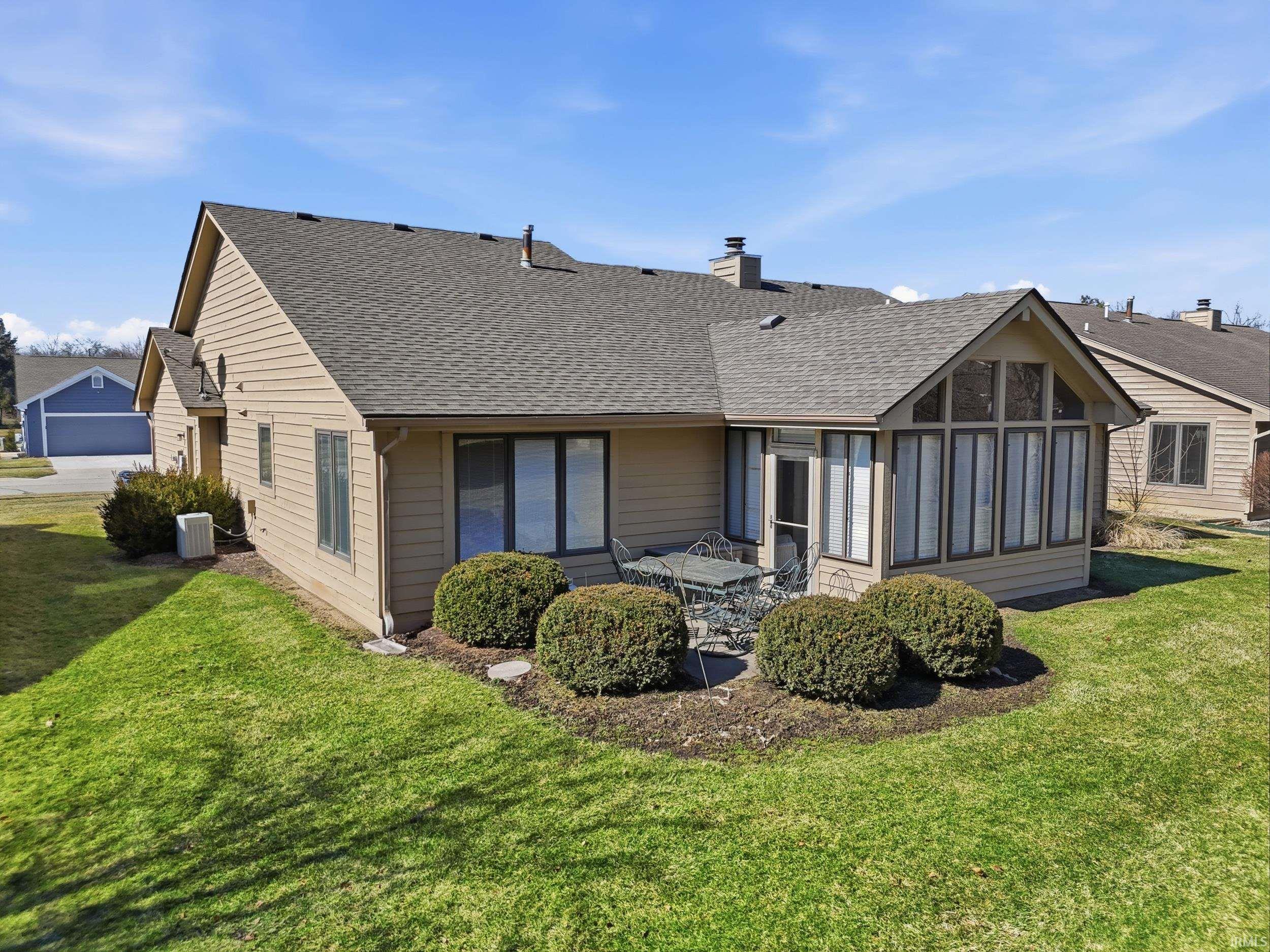 Rear view of property featuring a shingled roof, a sunroom, a yard, and a chimney