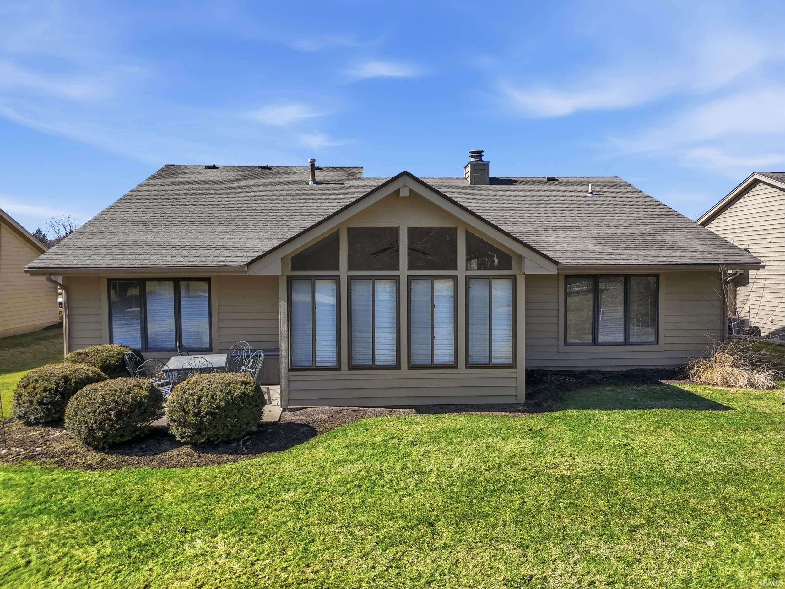 Back of property with roof with shingles, a chimney, and a yard